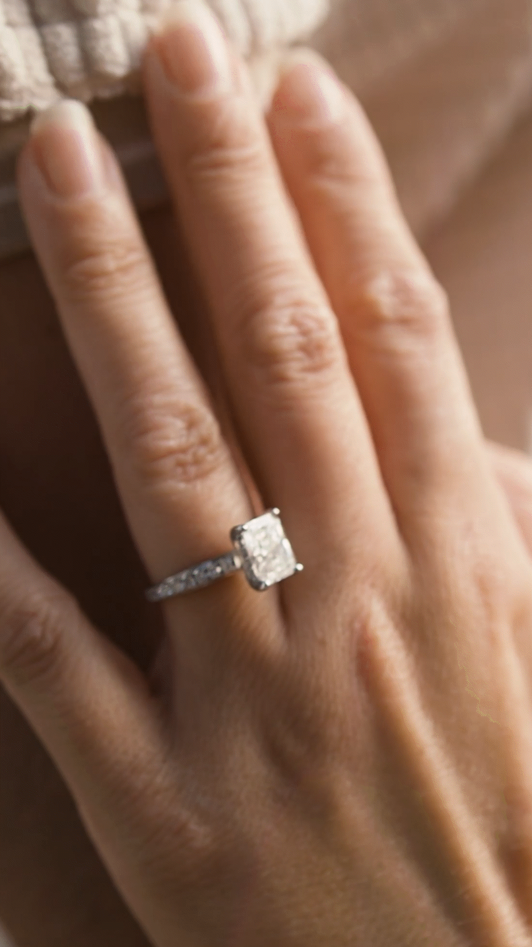 Close-up of a woman's hand with an engagement ring featuring a large square diamond on her ring finger.