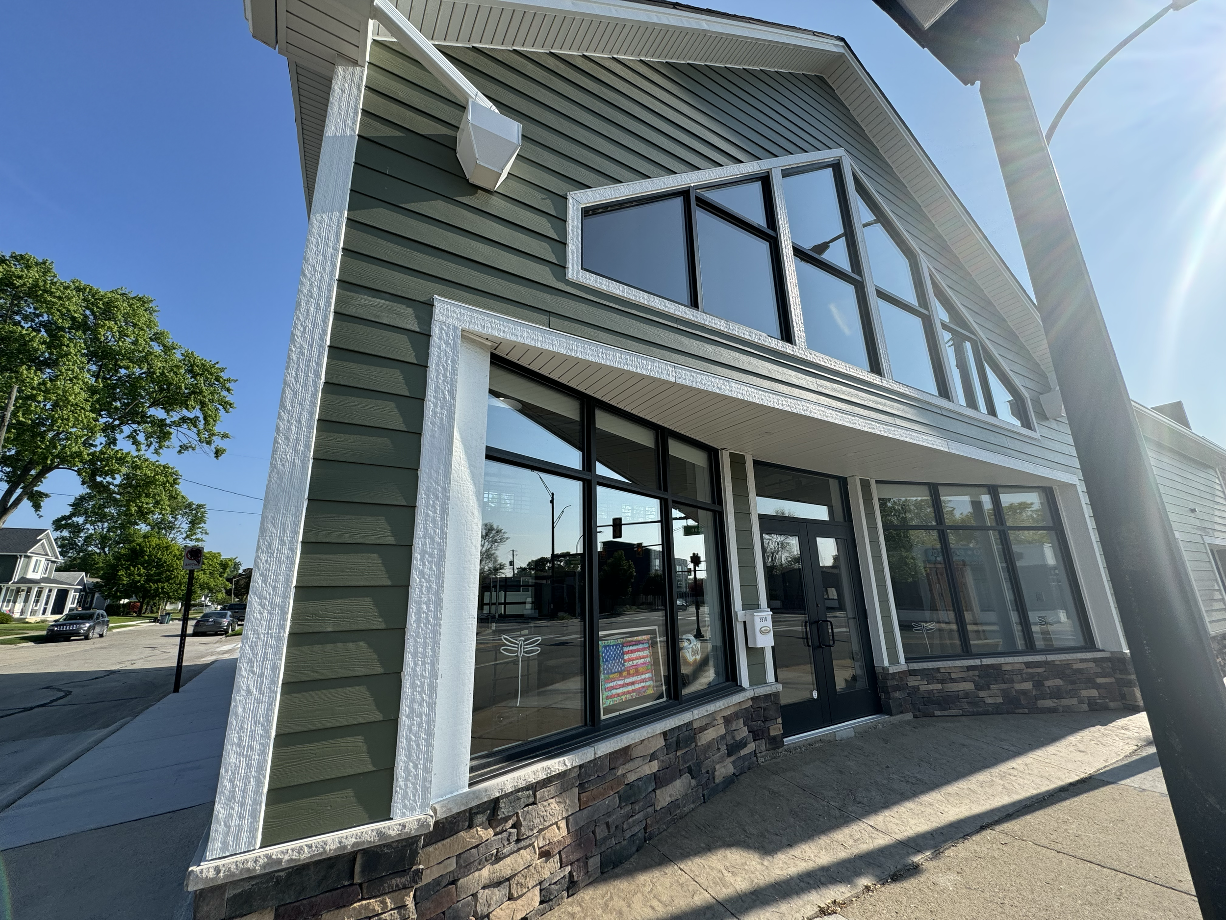 Modern commercial building in Berkley, MI with oversized windows, green siding, and stone veneer — designed and built by Motor City Construction.