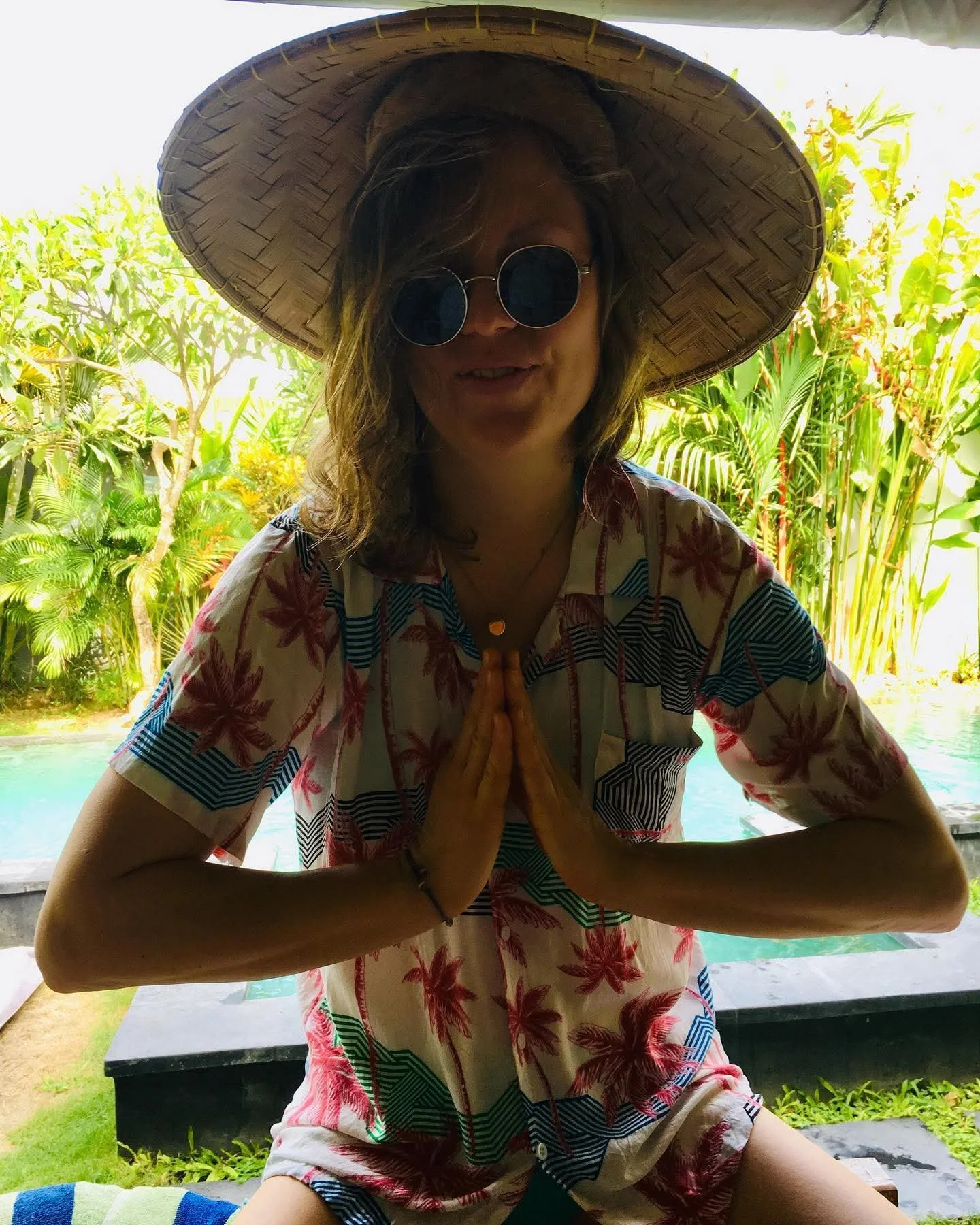 Maša in Meditationshaltung mit Strohhut am Pool.