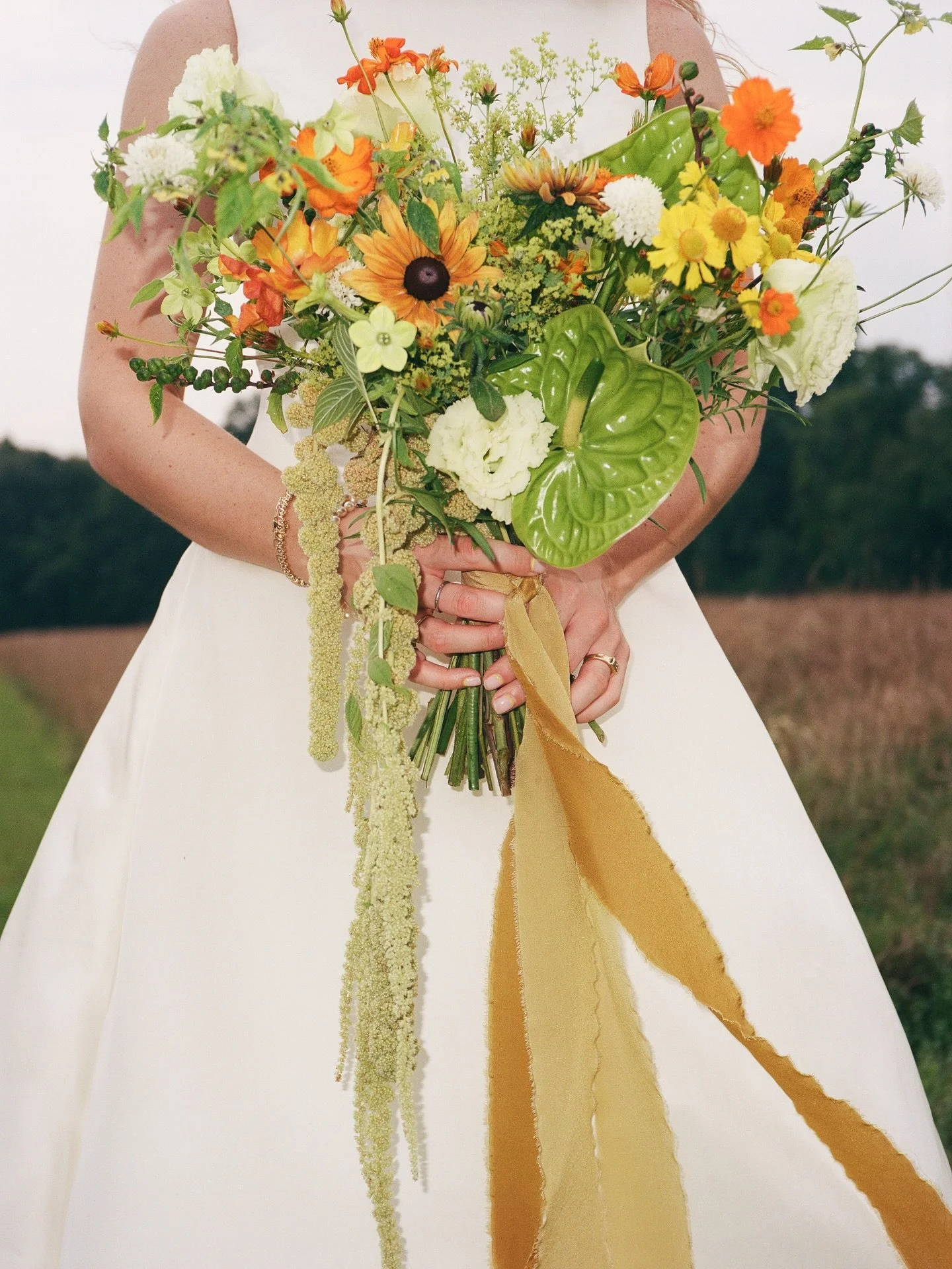 Lush greenery with oranges, yellows, and a touch of white brought movement and energy to the bouquet and chuppah. Grounded florals anchored the design, rooted in nature and tailored for the moment, creating a look that felt dynamic and memorable.

Pl