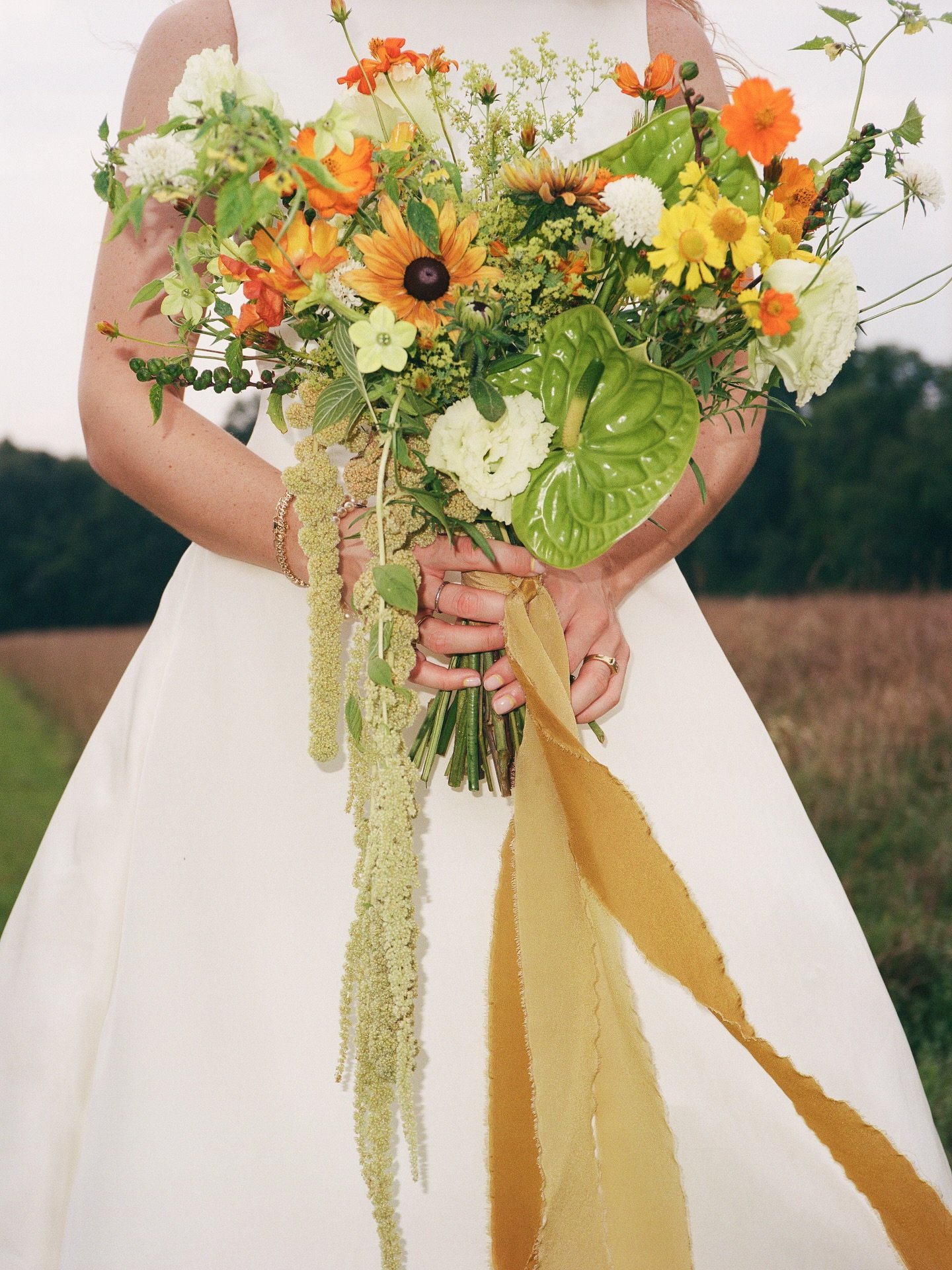 Lush greenery with oranges, yellows, and a touch of white brought movement and energy to the bouquet and chuppah. Grounded florals anchored the design, rooted in nature and tailored for the moment, creating a look that felt dynamic and memorable.

Pl