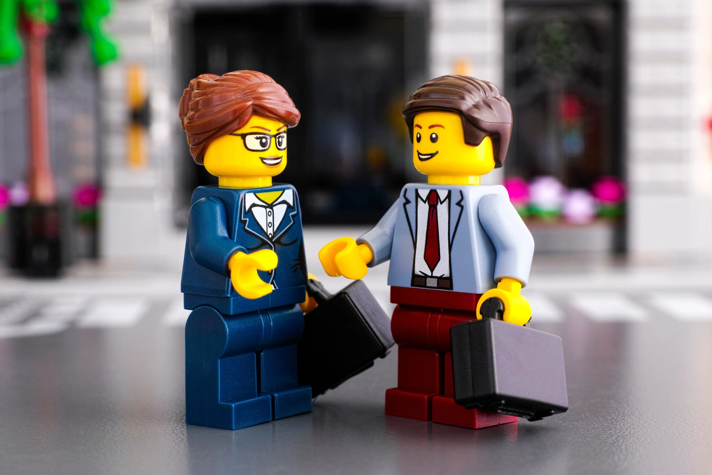 A female and male minifigure that are in business attire, carrying briefcases, with smiles are their faces.