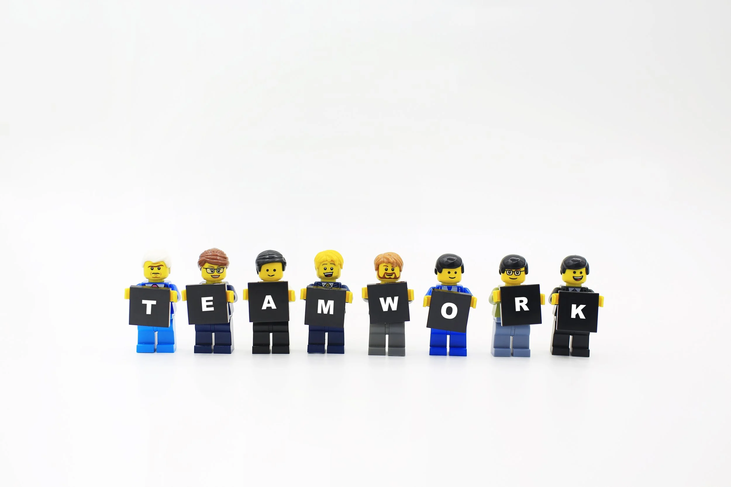 LEGO minifigures holding "Teamwork" bricks