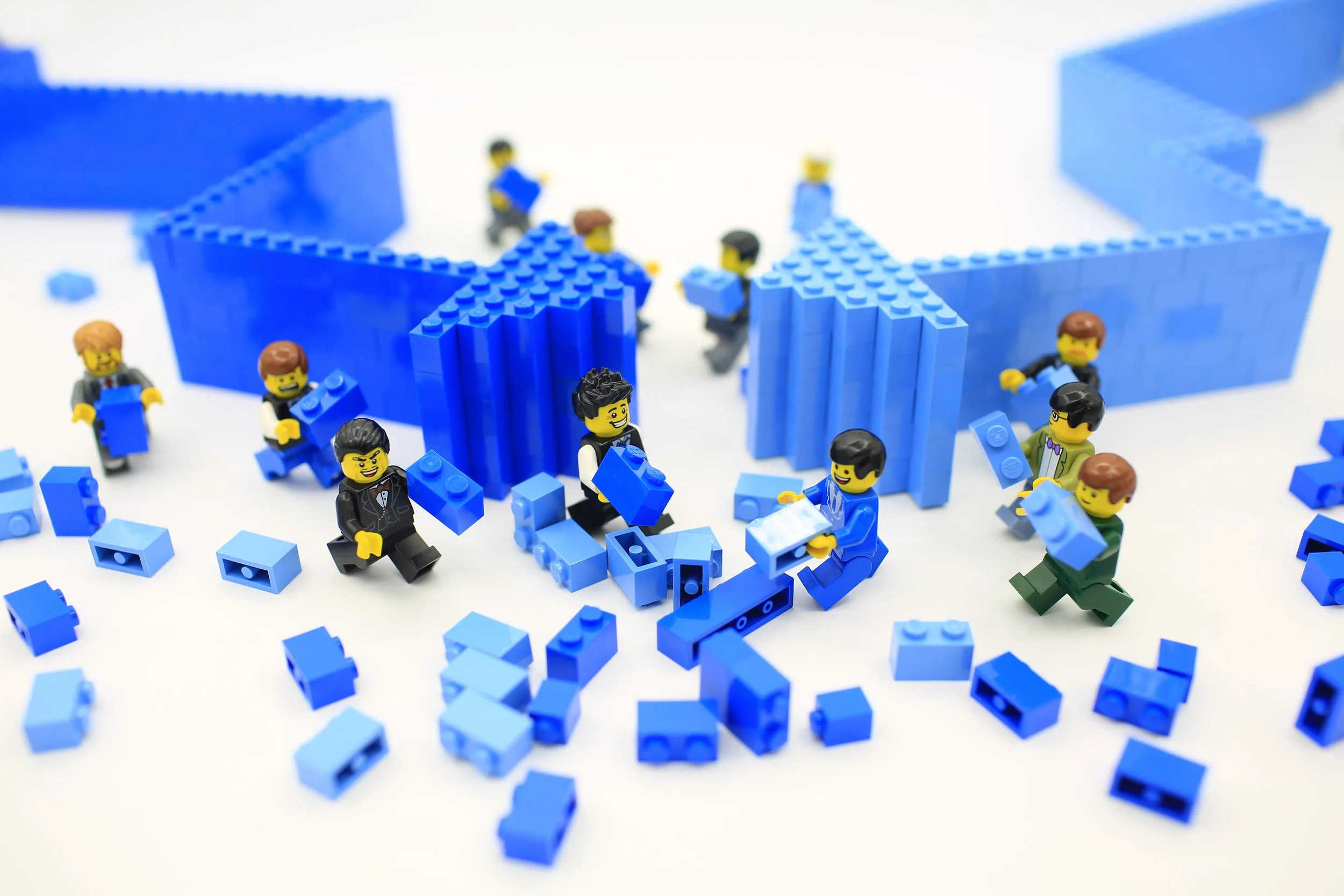 LEGO minifigures using blue bricks to build business arrows that face each other.