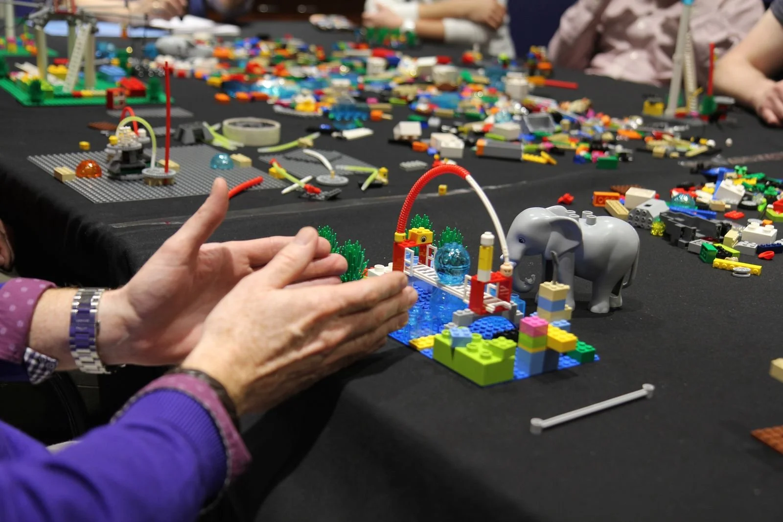 Hands held in a position that looks like someone is talking about the LEGO model that is front of them.