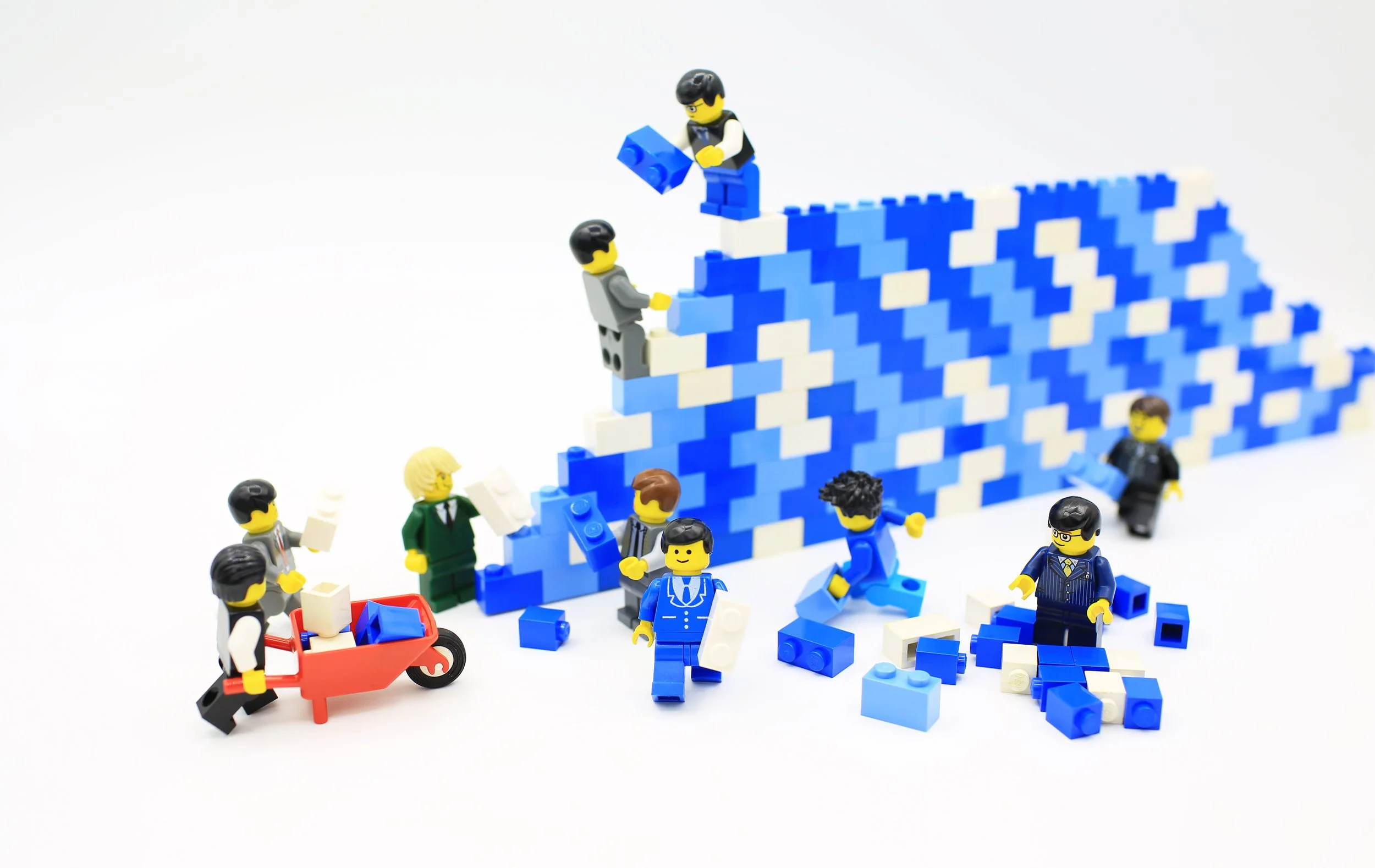 LEGO minifigures building a wall with blue bricks.