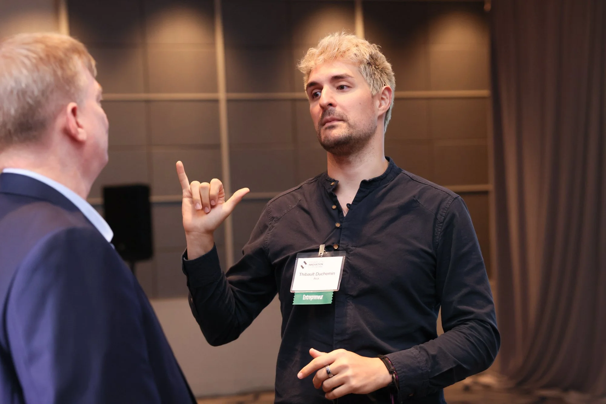 Founder at the 2025 DIF using sign language to network in the audience