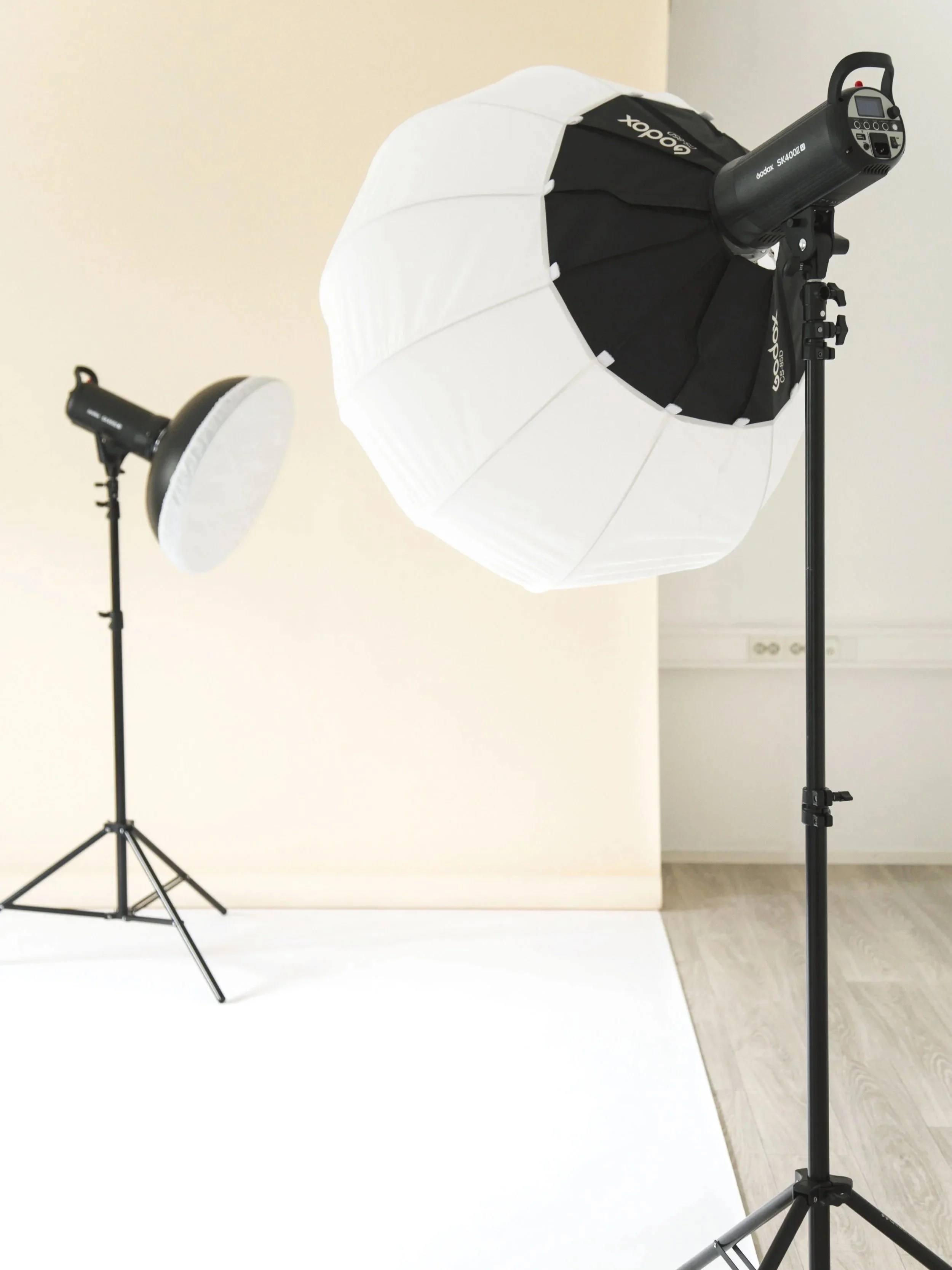 Valokuva valokuvastudiosta, jossa on kaksi valokehää ja valkoista taustaa.