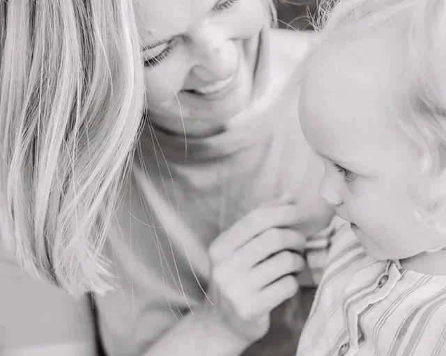 Nainen ja pieni lapsi katselevat toisiaan läheisesti, hymyilevät, harmaasävykuva
