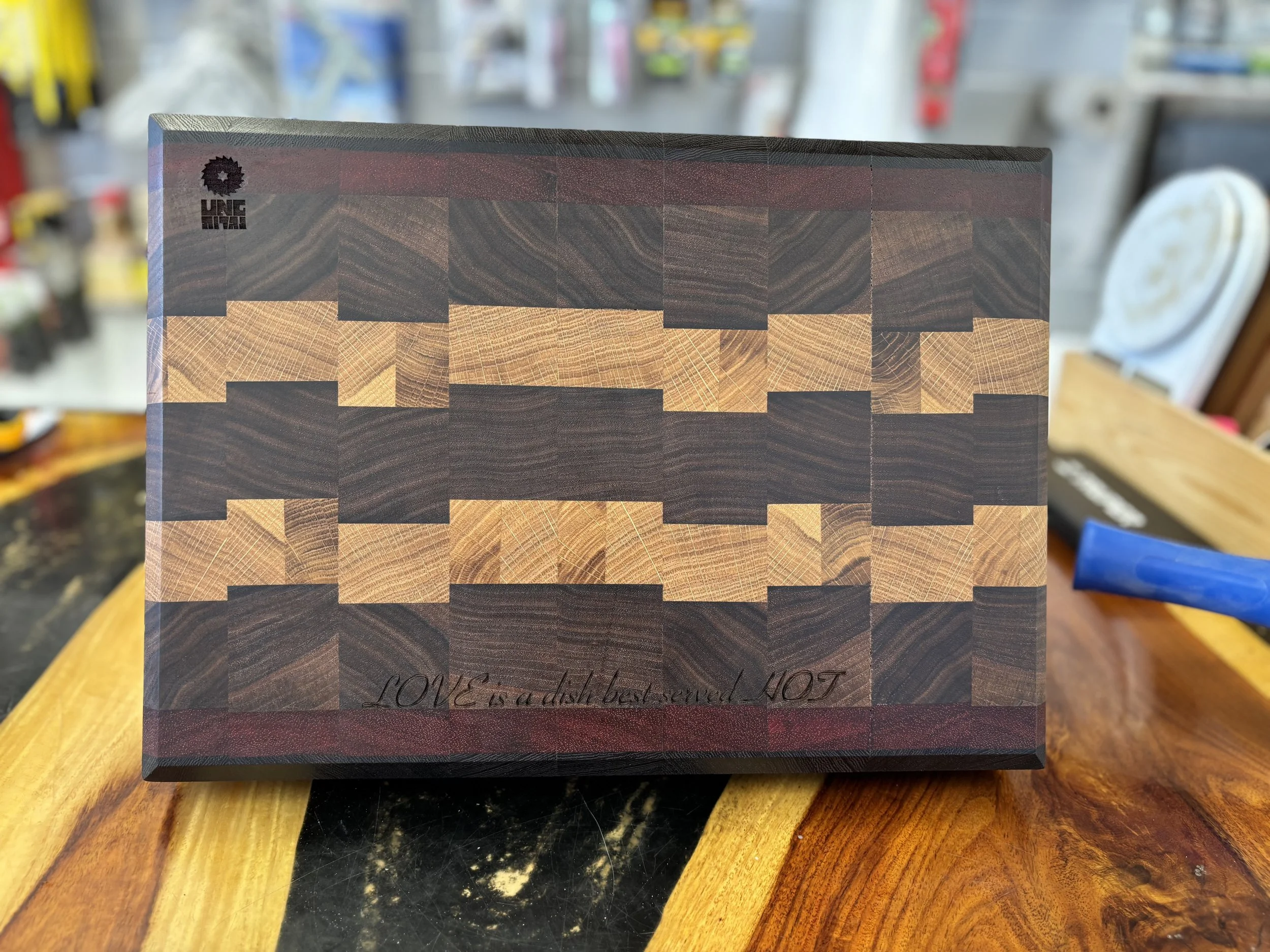 A wooden box with a geometric pattern in dark and light wood tones, placed on a wooden surface in a workshop setting.