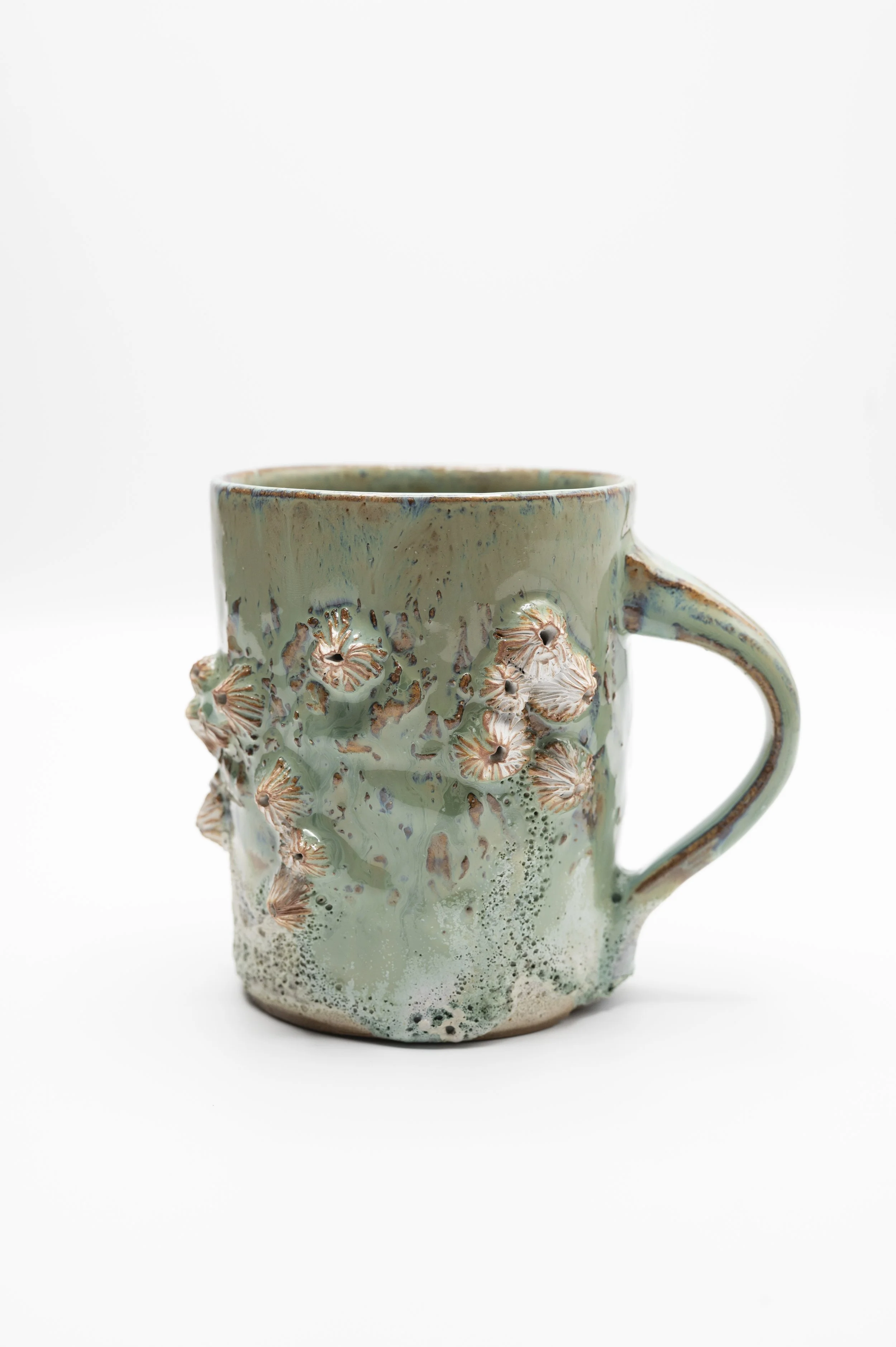 A ceramic mug with a textured floral design and a glossy glaze, featuring a handle on the right side, set against a plain white background.