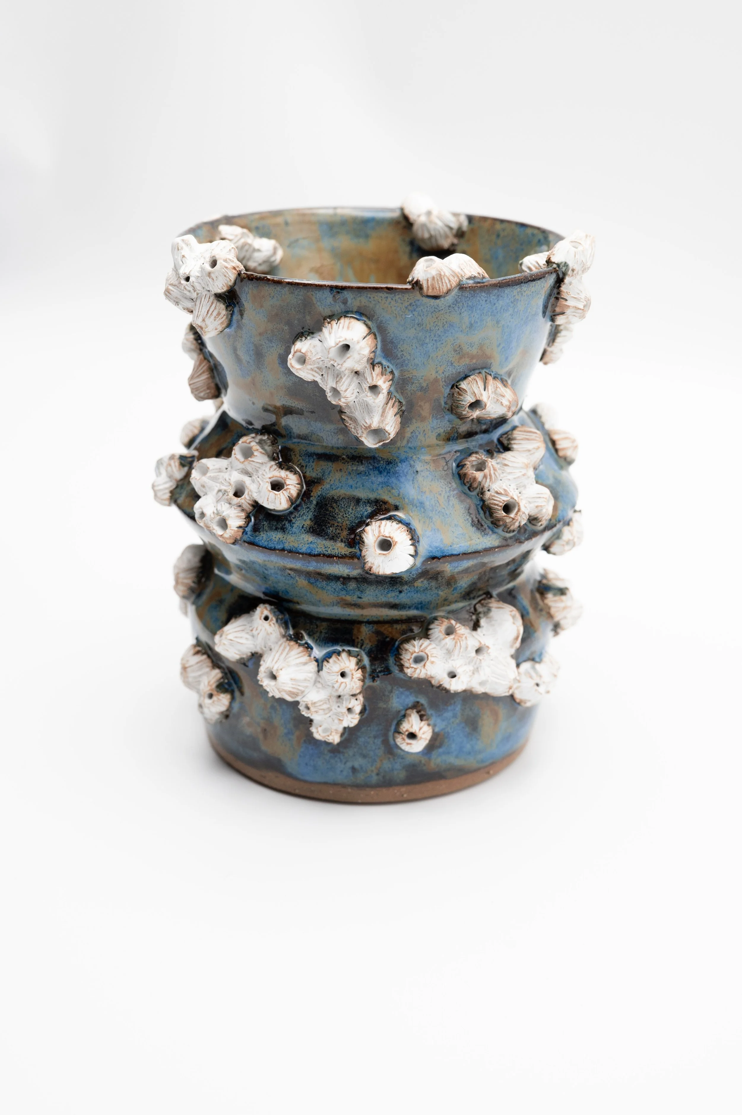 Ceramic vase with a blue glaze and 3D textured white flowers with brown accents all over the surface.