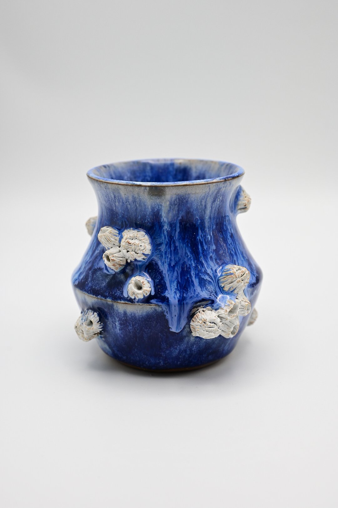 A blue ceramic vase with hand-sculpted barnacles.