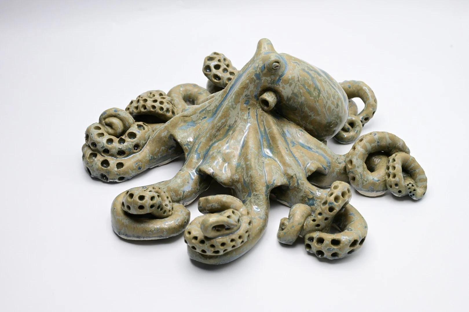 Ceramic sculpture of an octopus with detailed tentacles, set against a white background.