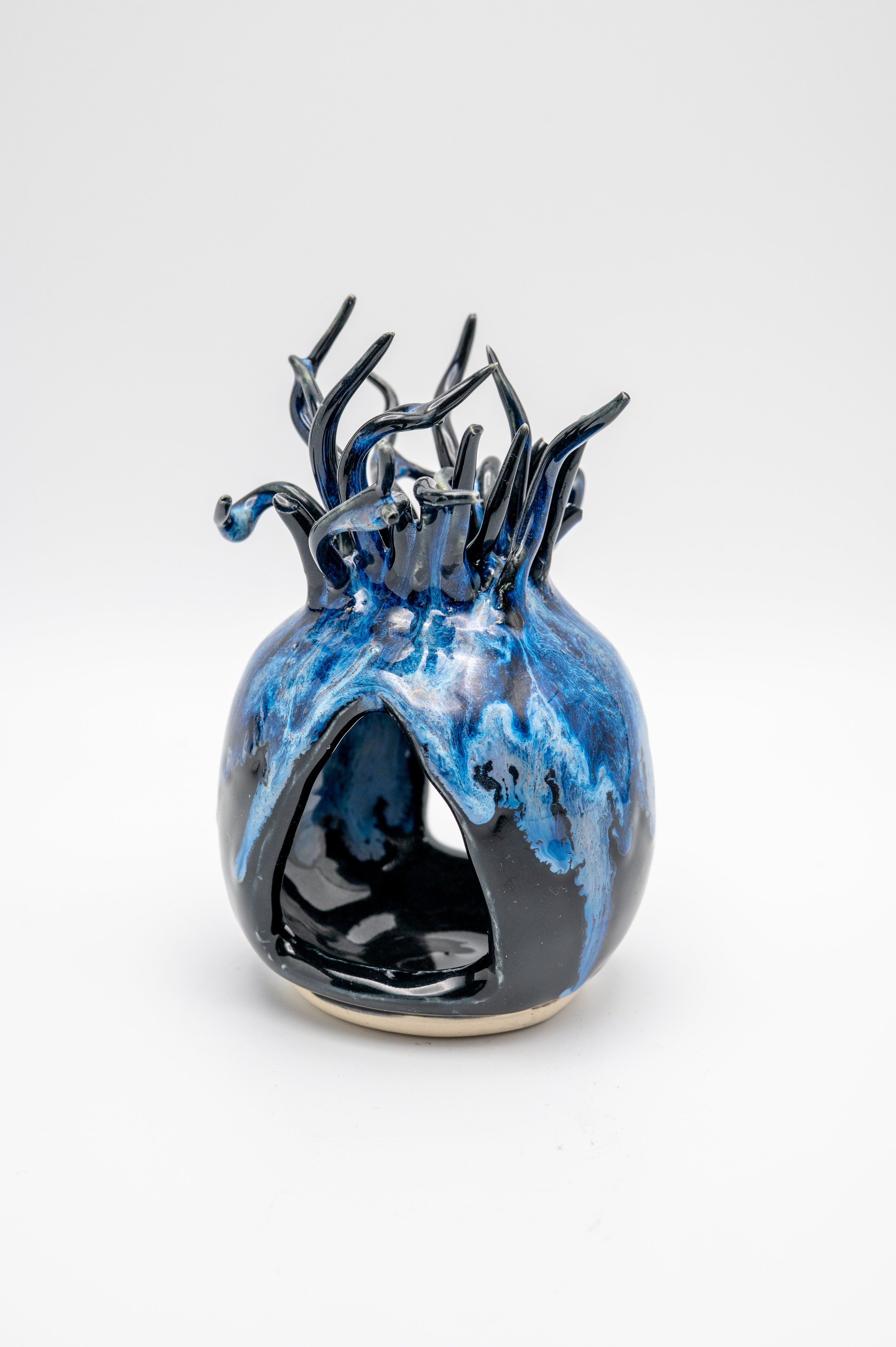 A ceramic vase with a blue and black marbled pattern and black glass-like decorative elements protruding from the top.