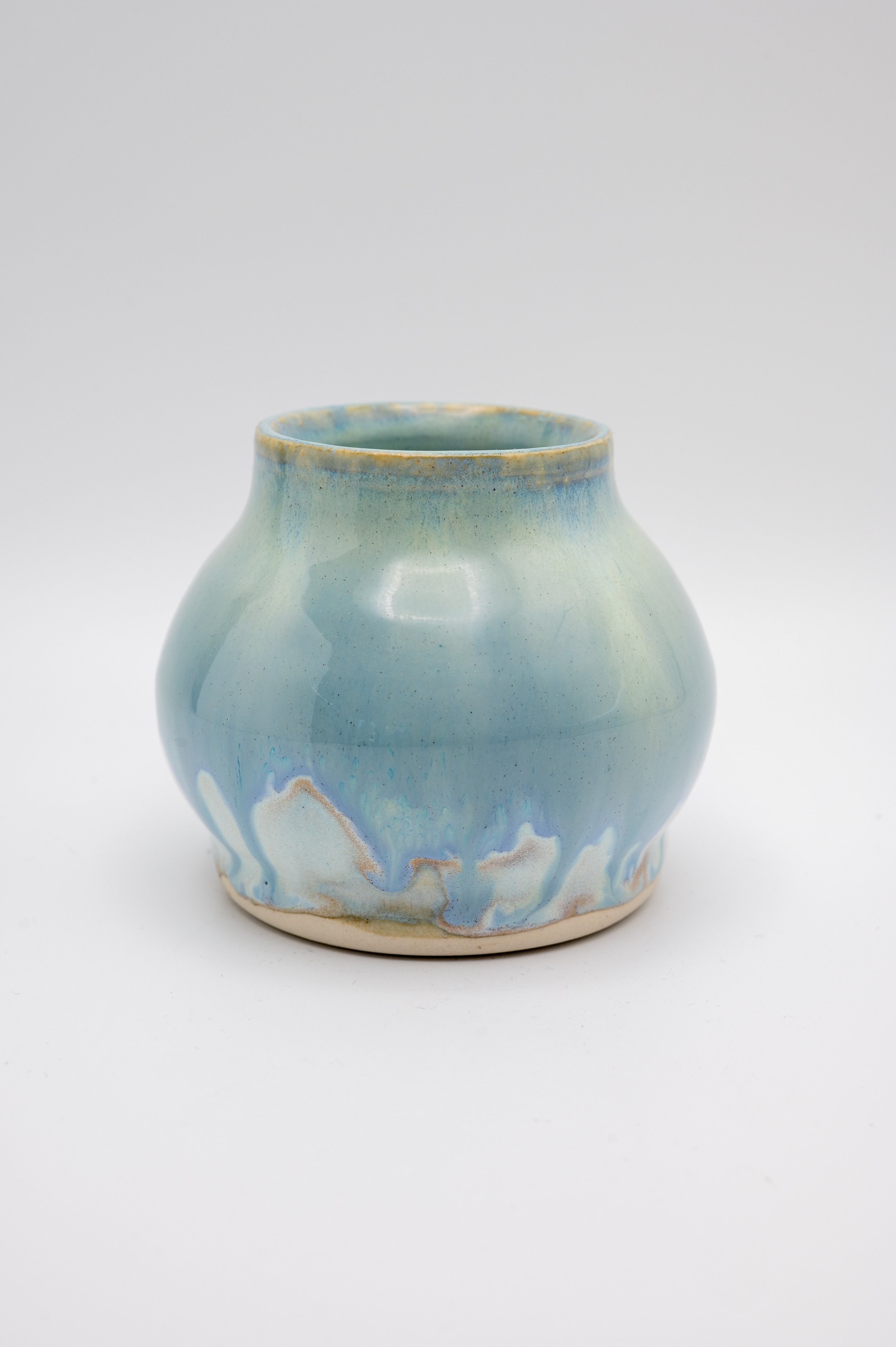 A ceramic vase with a glossy light blue glaze and marbled patterns in shades of white, beige, and blue, set against a plain white background.