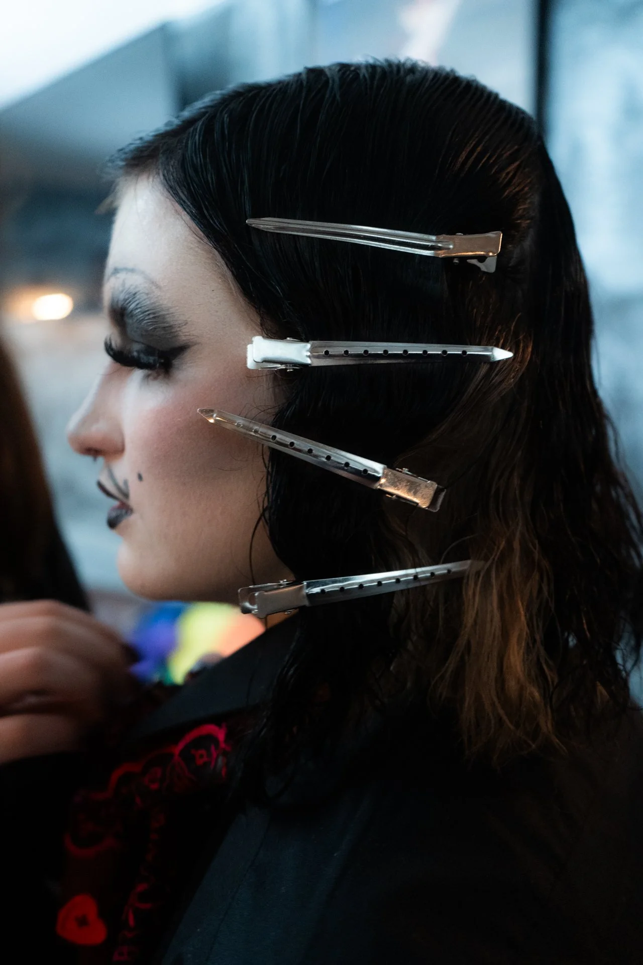 A woman with dark hair and makeup, with four hair clips securing her hair in place.