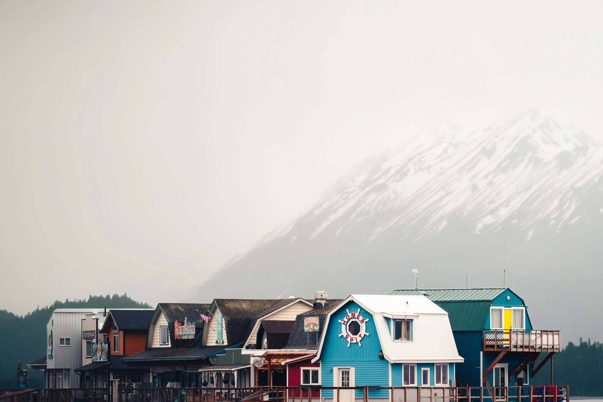 Colorful row of houses at the waterfront with a snow-capped mountain in the background. Homer, Alaska