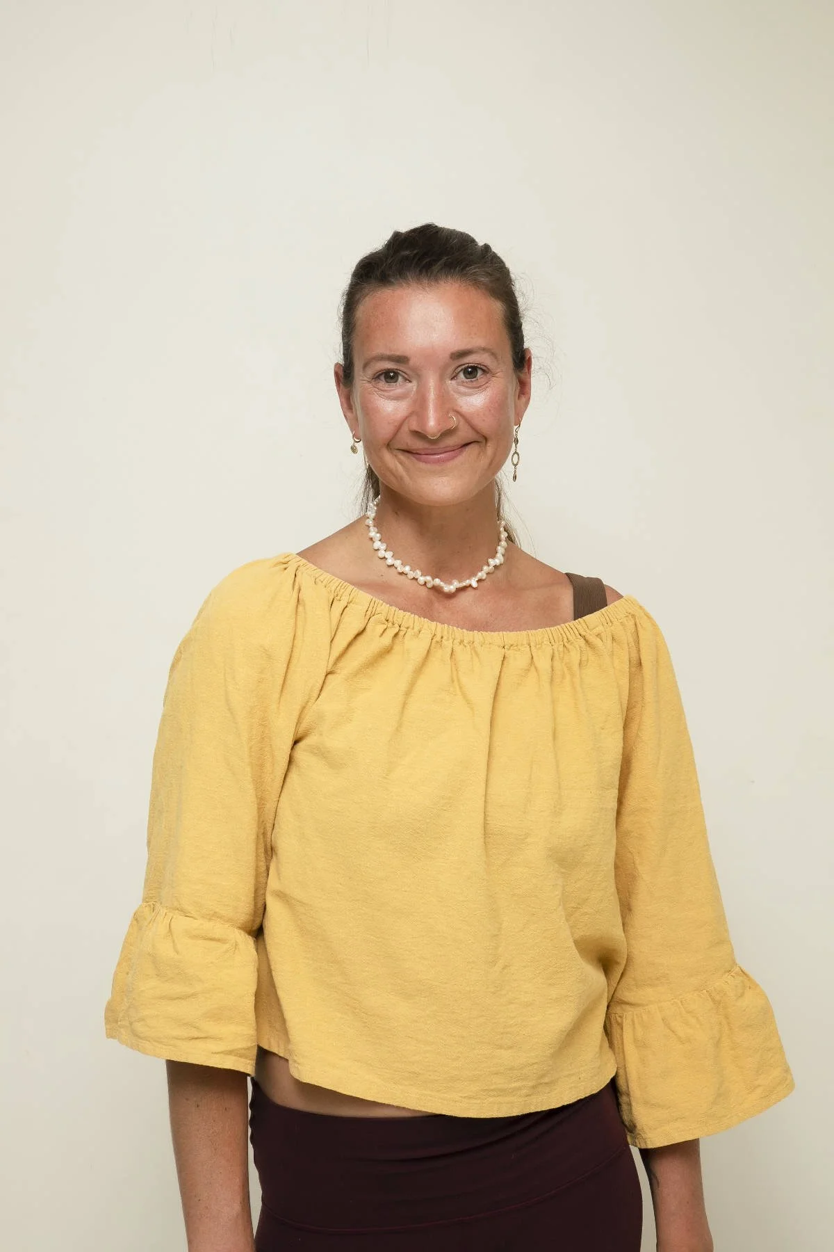 Woman smiling with hands in prayer pose by the ocean