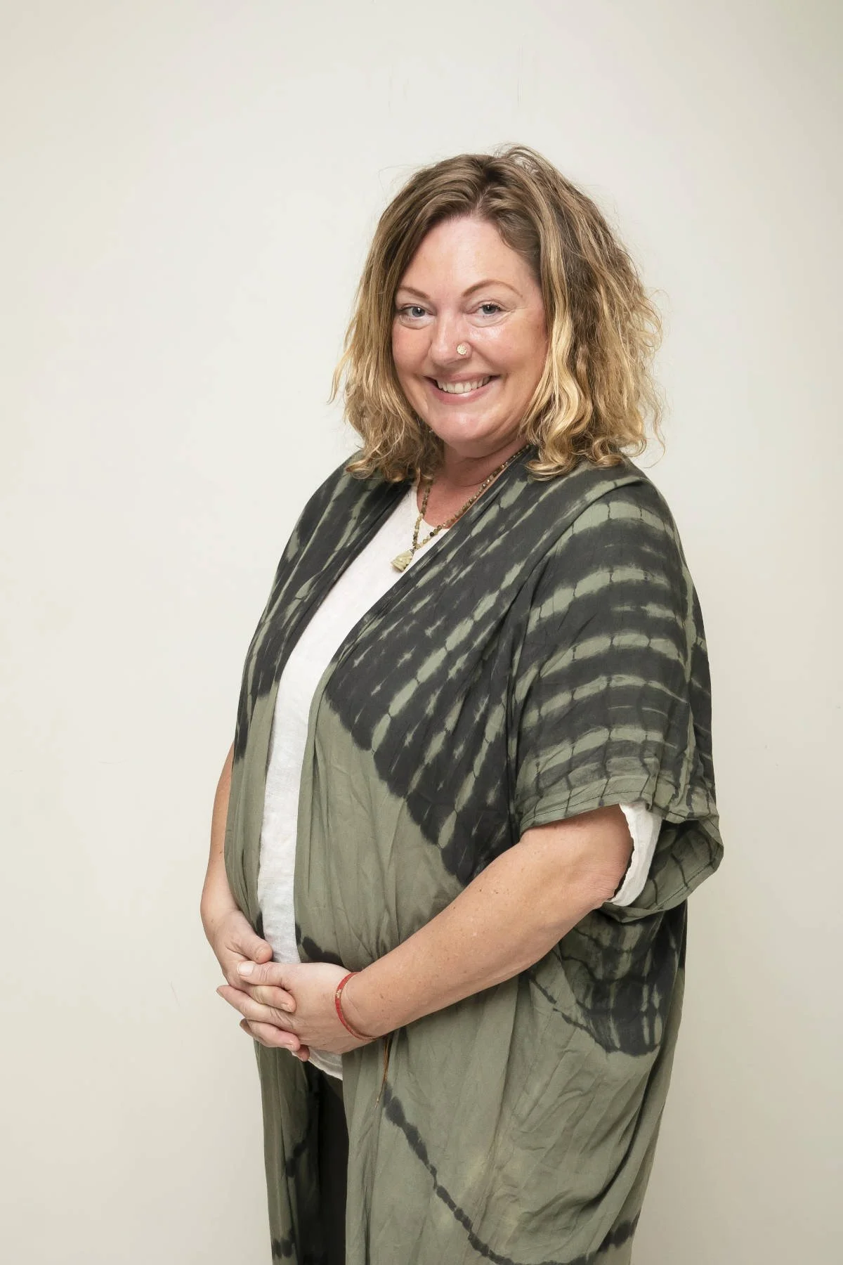 Person joyfully playing with two small brown dogs on a patterned rug outdoors, with one leg playfully raised in the air.