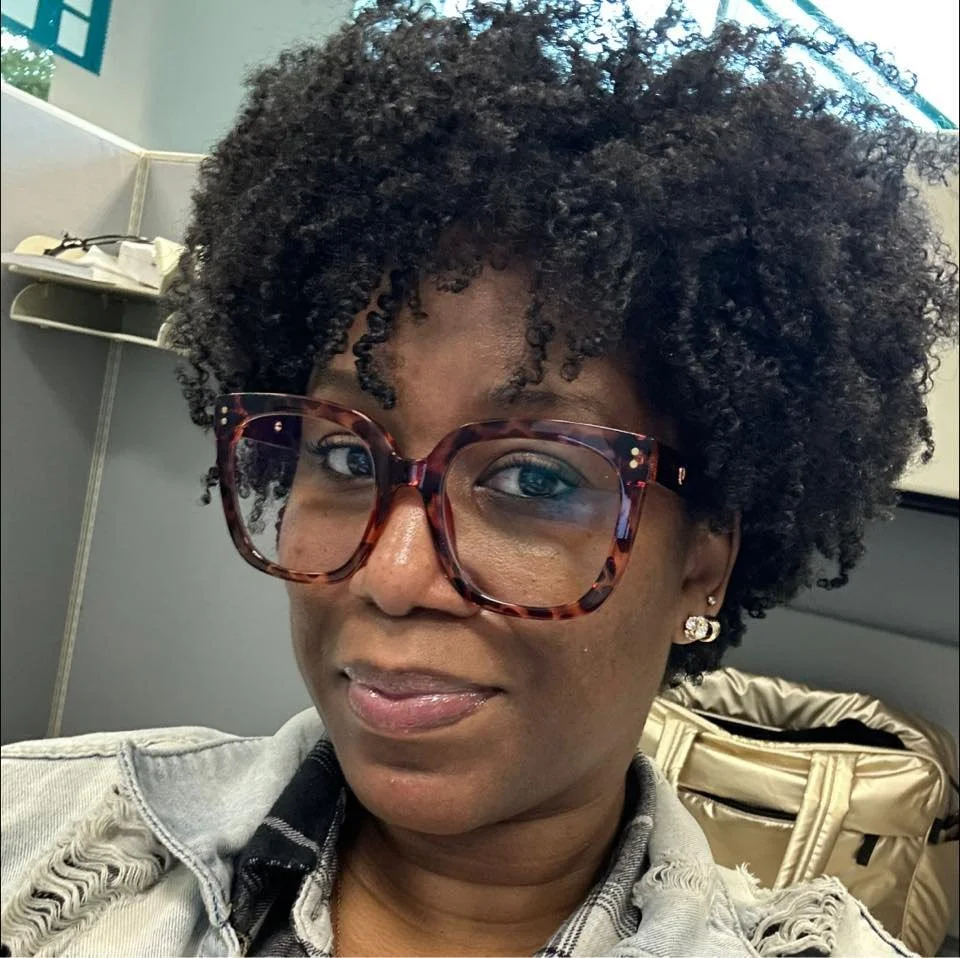 Smiling female client with curly hair and glasses, providing a testimonial for the inclusive fitness community at 901fitlife.