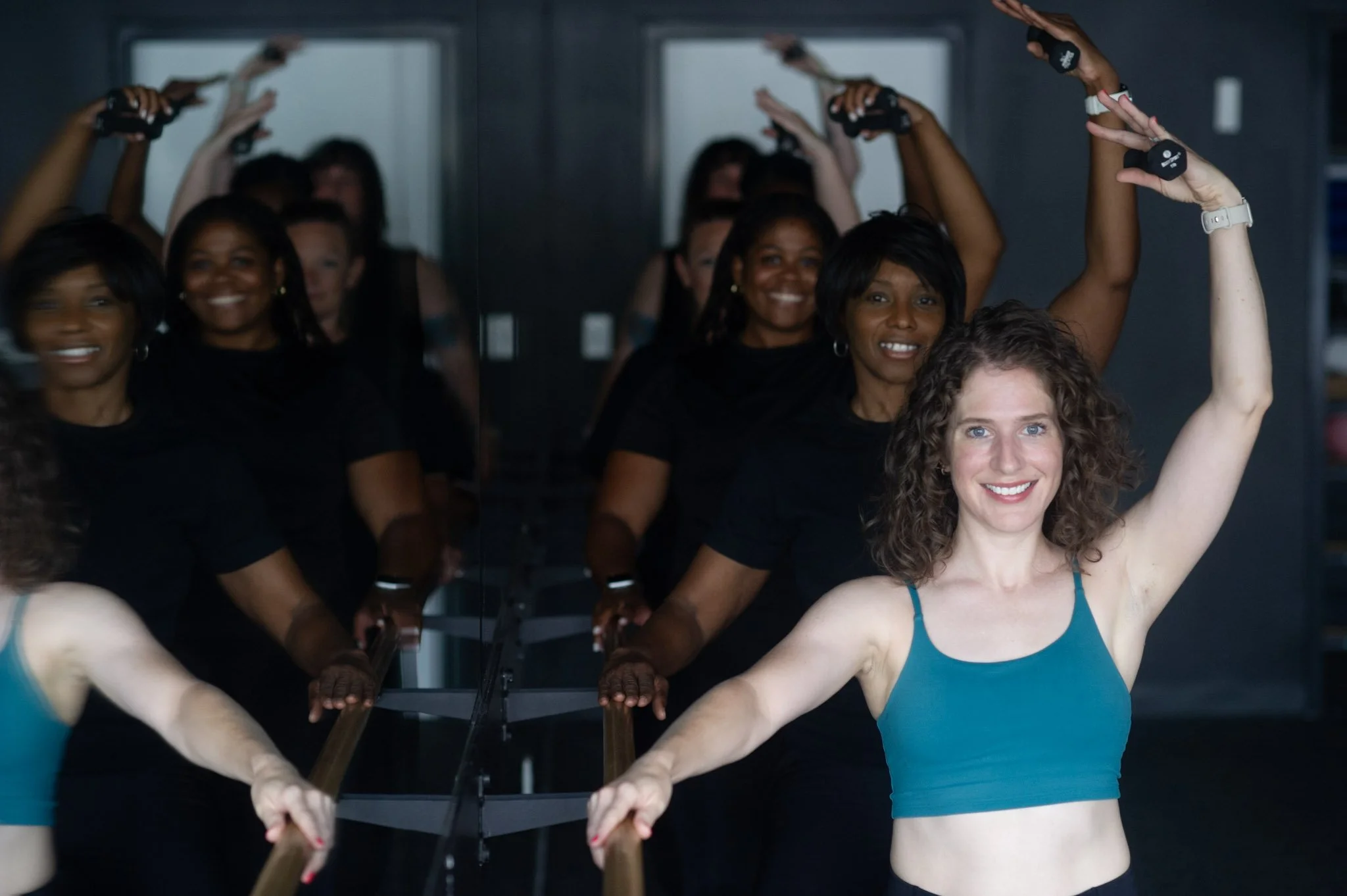 A diverse group of women participating in a barre fitness class at 901fitlife Memphis, using ballet barres for low-impact strength and flexibility.