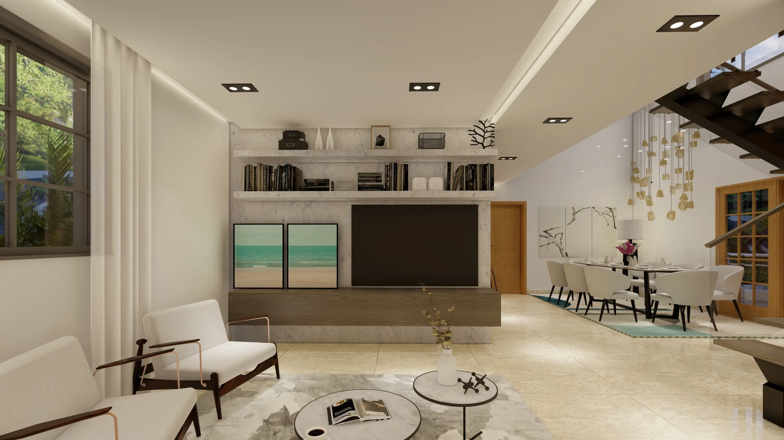 Sala de estar moderna con muebles blancos y decoración minimalista. Tiene una pared con estantería, libros, y dos cuadros de paisaje de playa. Hay un comedor al fondo con mesa y sillas alrededor de una lámpara colgante.