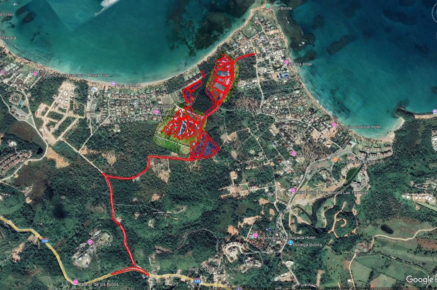 Vista satelital de una zona costera con playas, vegetación, carreteras y áreas urbanas. El área está etiquetada con nombres de hoteles y playas, con líneas rojas marcando ciertos límites o rutas.