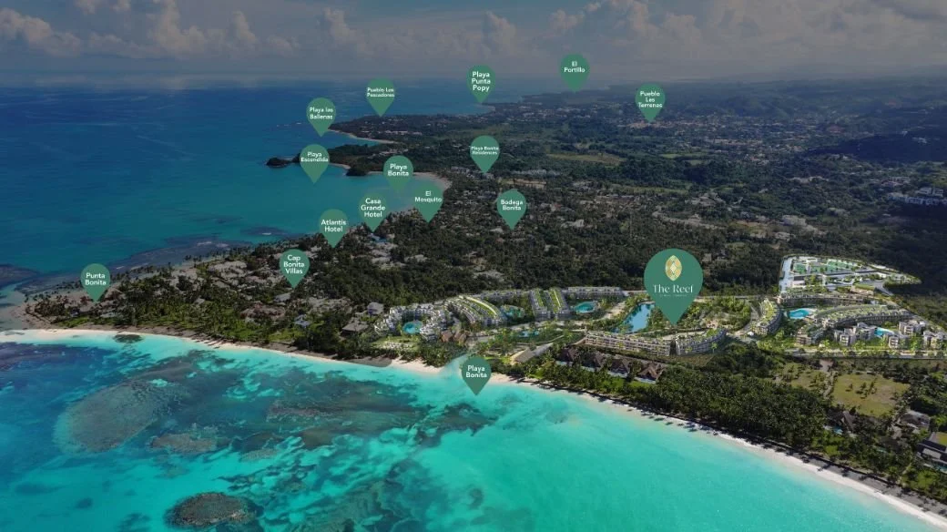 Vista aérea de una playa tropical con agua turquesa y varias ubicaciones señaladas, como hoteles y playas, en el paisaje circundante.