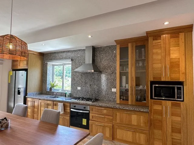 Modern kitchen with wooden cabinets, granite countertops, stainless steel appliances, and a central dining table.