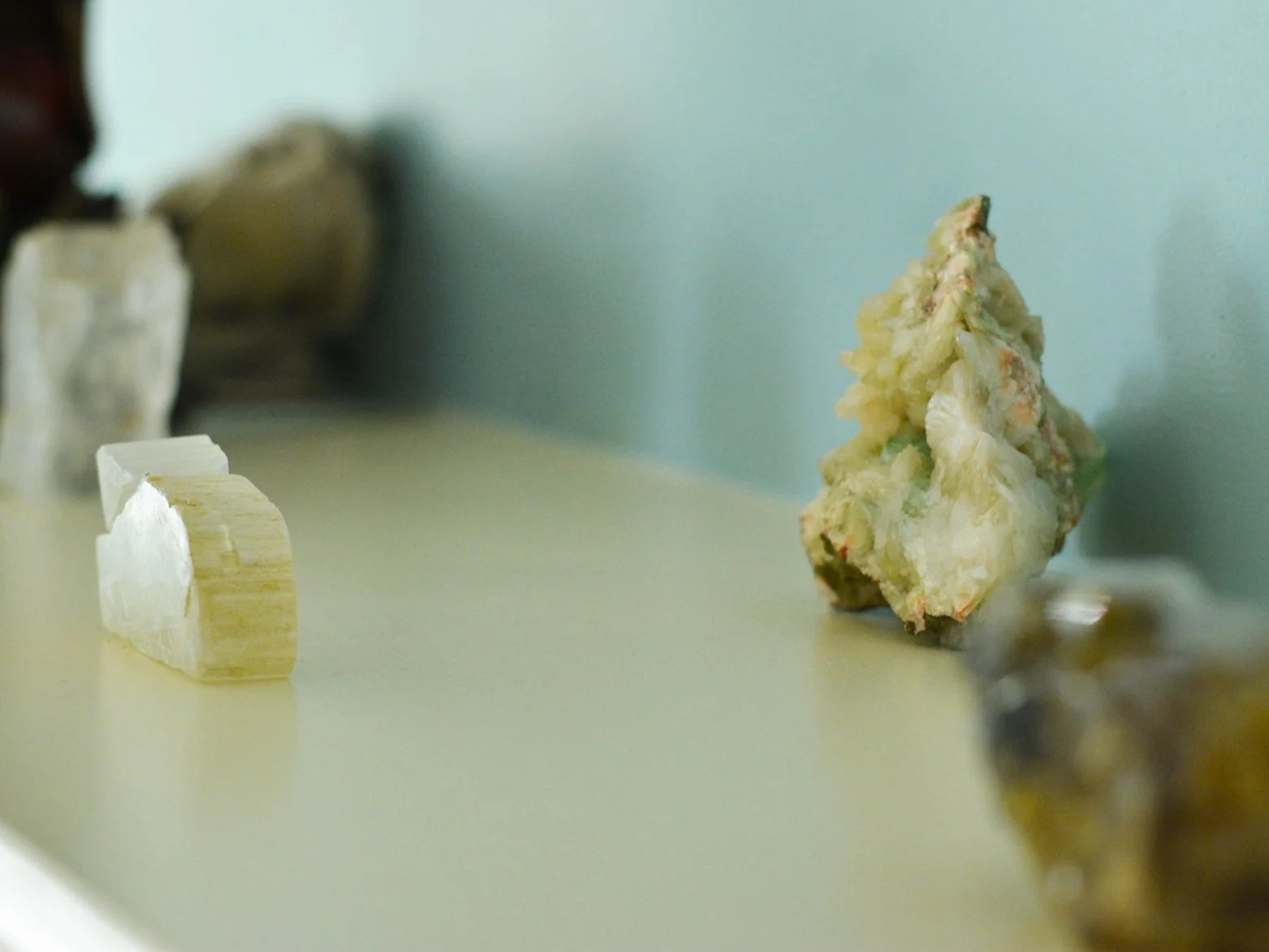 Raw crystals and healing stones on a sunlit shelf, setting a calm, grounded tone for astrology readings with Meghan MacKenzie