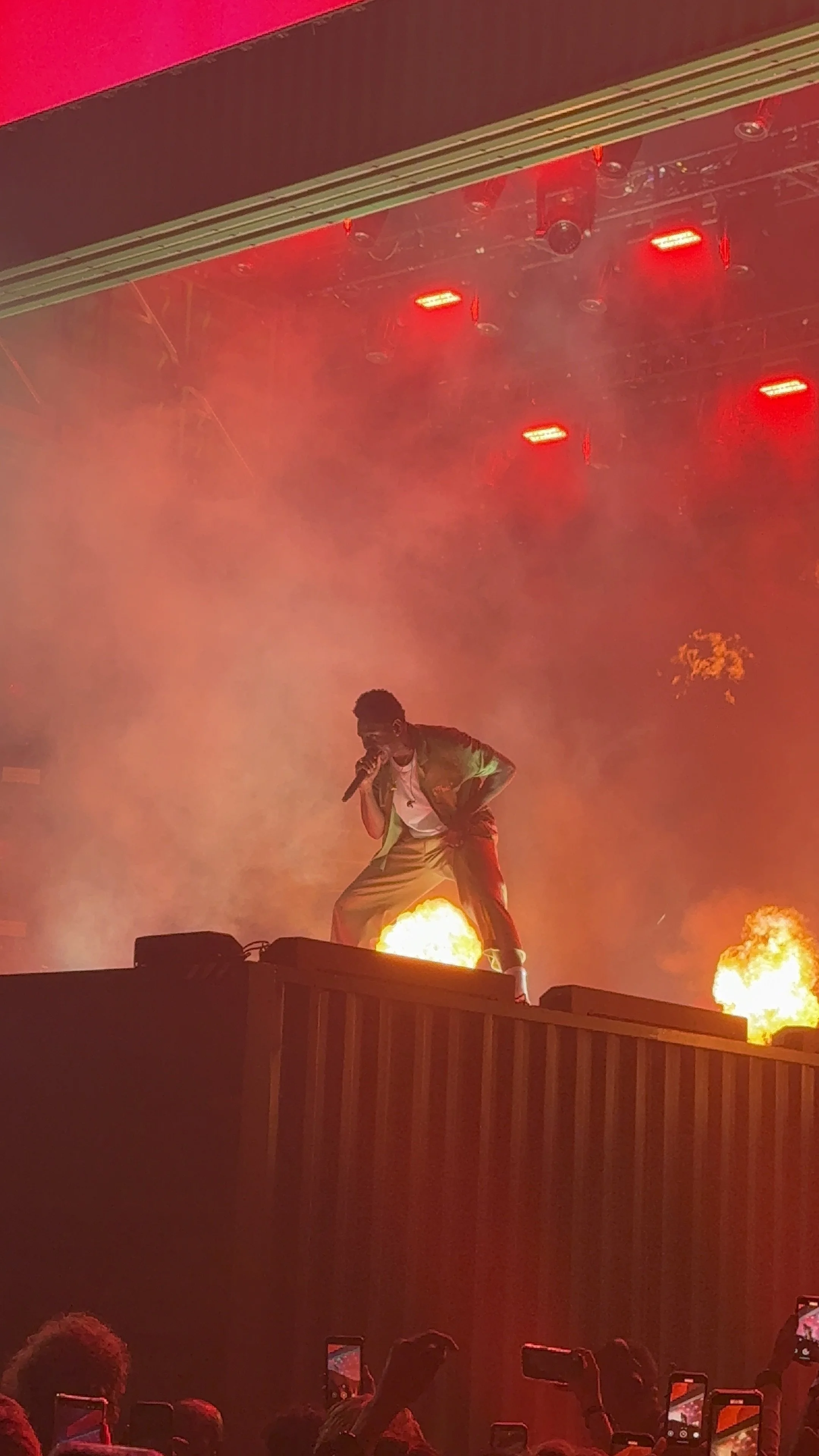 Performer on stage surrounded by fire and red lights, singing into a microphone during a concert. Tyler, the Creator O2 Arena London