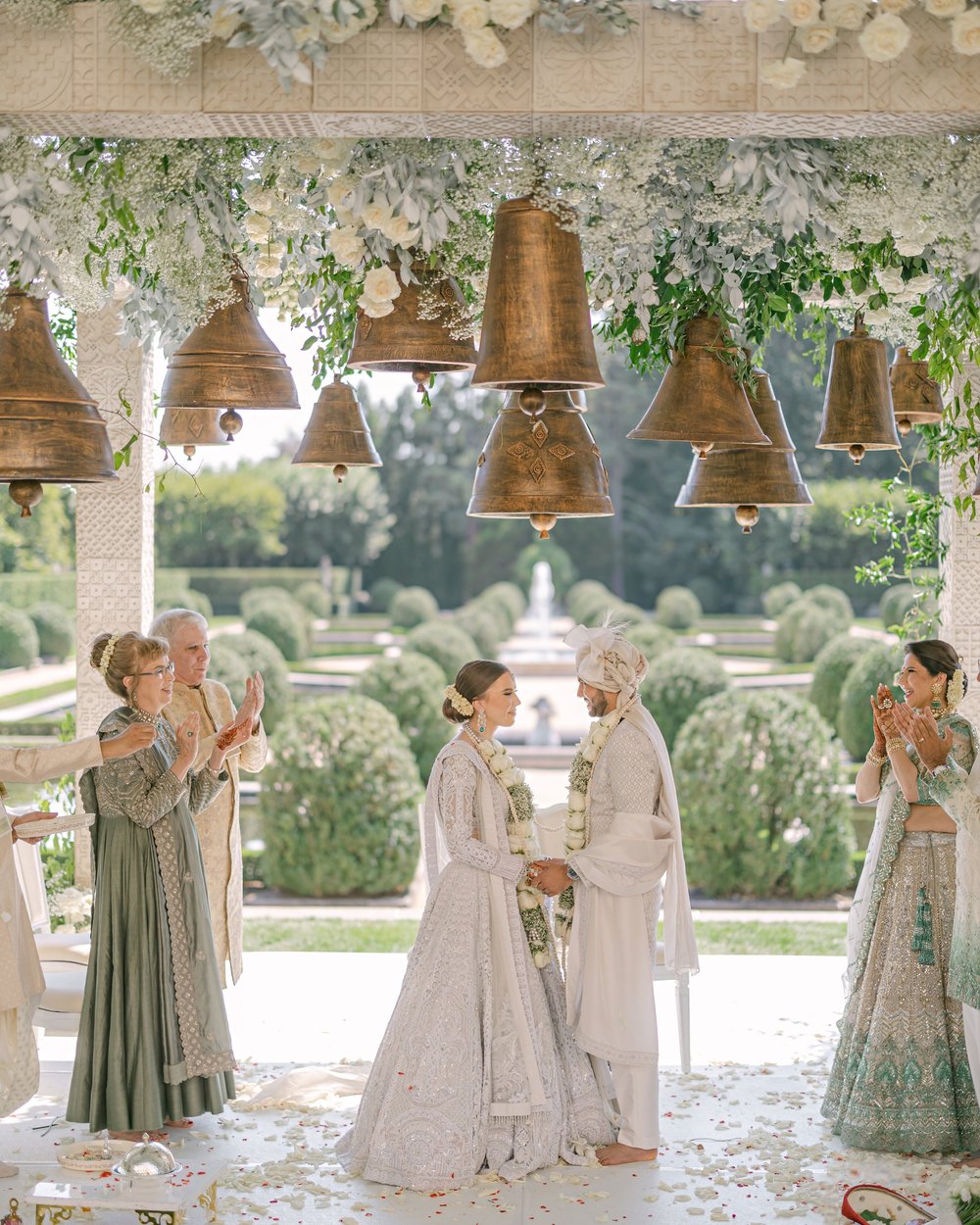 A ceremony beneath hanging brass bells and white florals at Oheka Castle