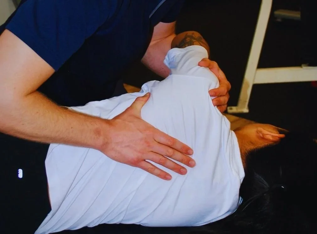 A person performing CPR on an unconscious individual lying on the floor, with hands on their chest.