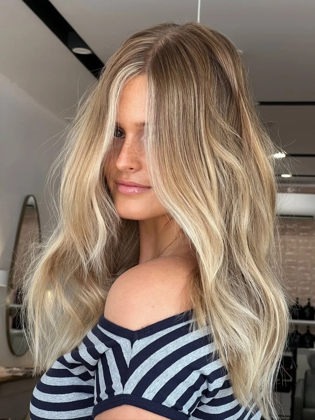 Lived-in blonde with soft root melt and brighter mid-lengths and ends. Natural side light. Alt text: Lived-in blonde hair colour at HairyAdelaide hair salon, Mona Vale, Northern Beaches
