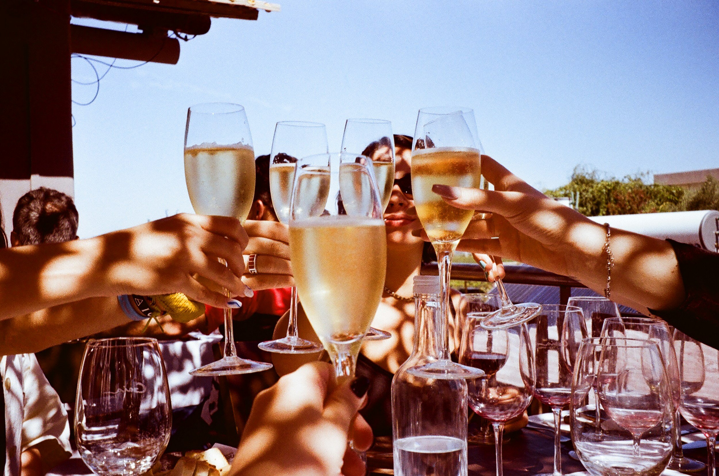 Friends celebrating and cheersing with glasses for champagne on a beautiful sunny day