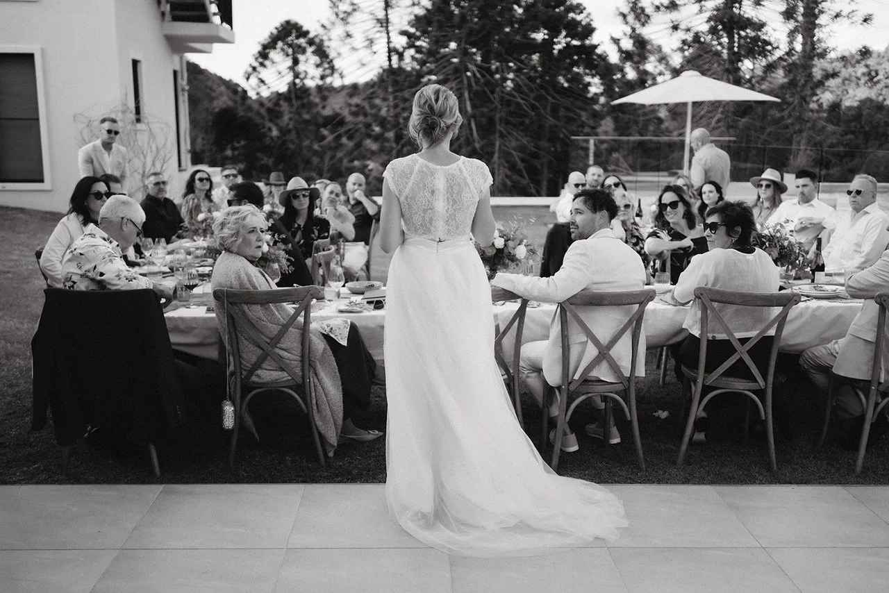 Beautiful bride giving speech surrounded by guests at charitable wedding experience - parties with purpose