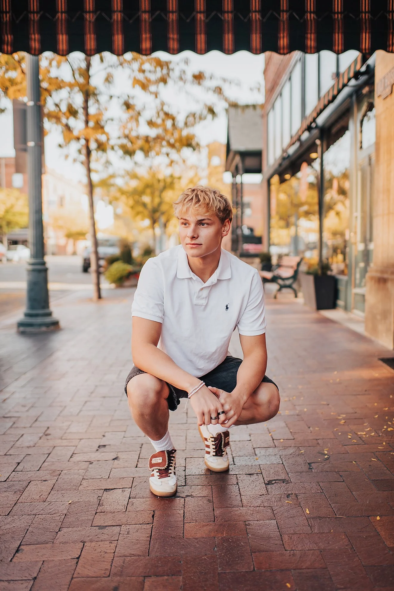 High school senior crouching casually on a brick walkway during a calm, natural senior session in Boise, Idaho