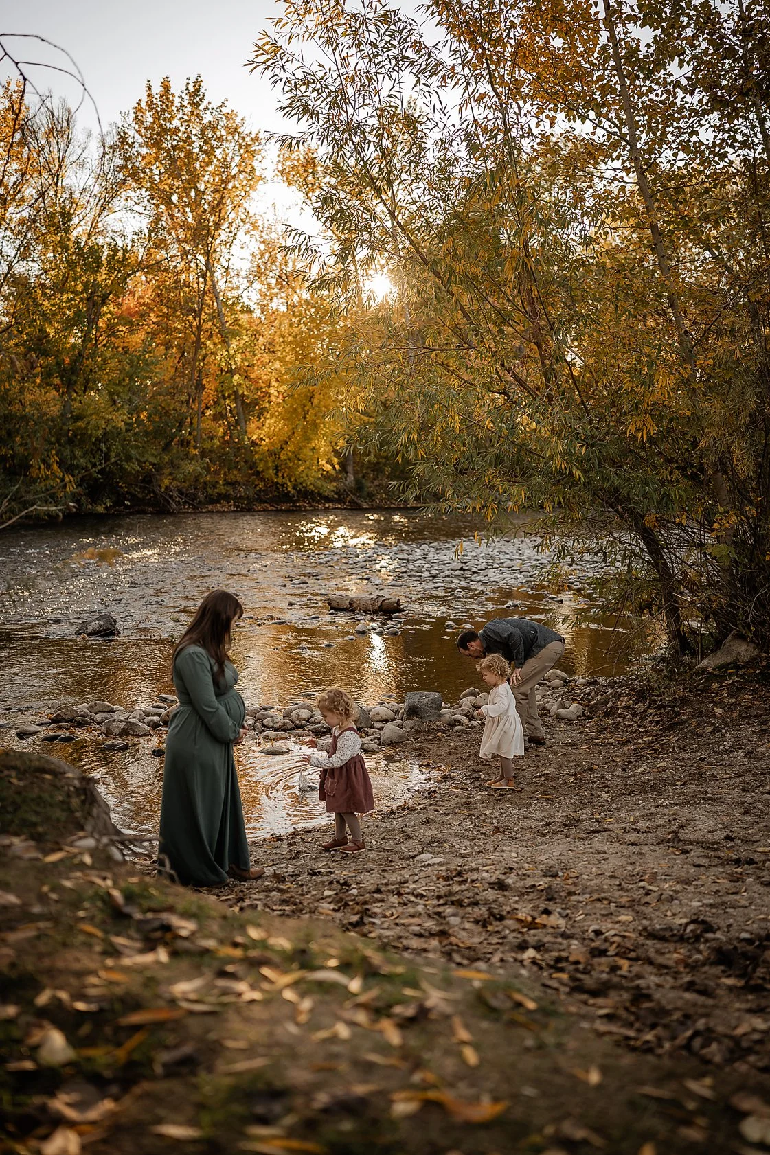 Family walking and playing together along a quiet creek during an autumn lifestyle session in Boise, Idaho.
