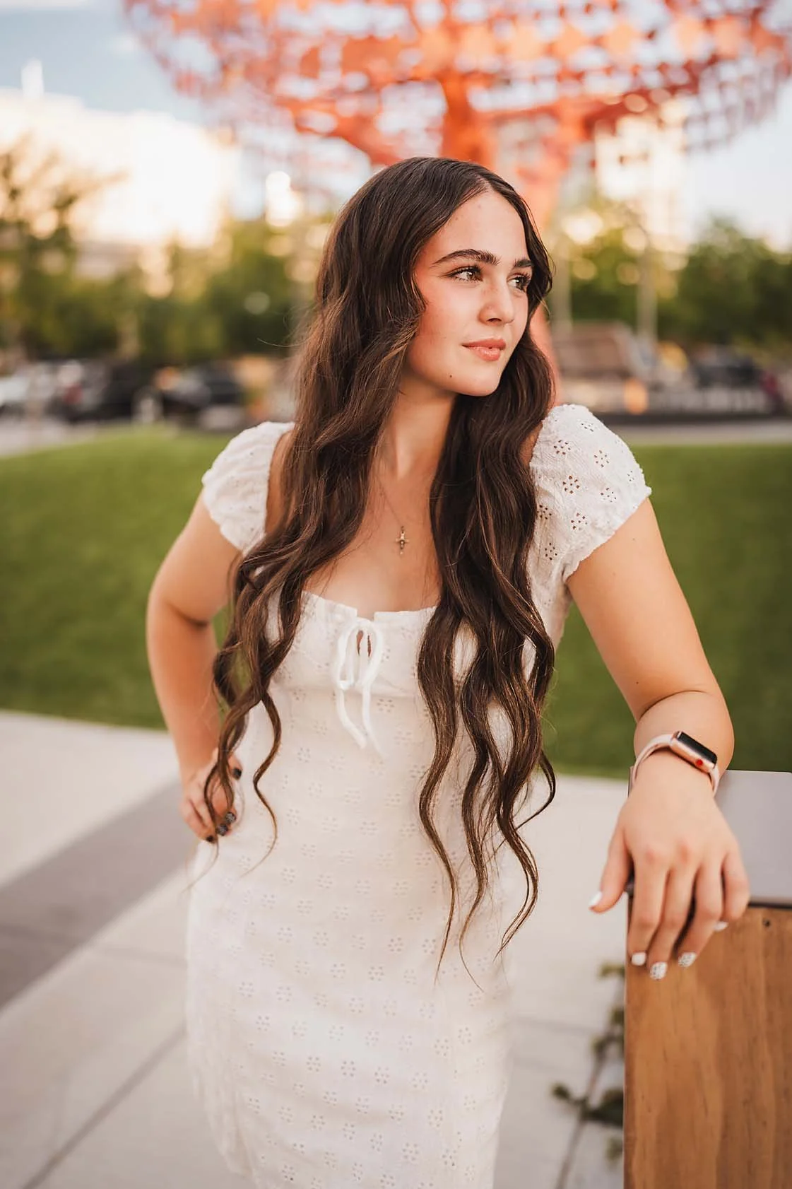 Eagle High School senior girl in a white dress looking off into golden light at a downtown Boise Idaho park during her senior session