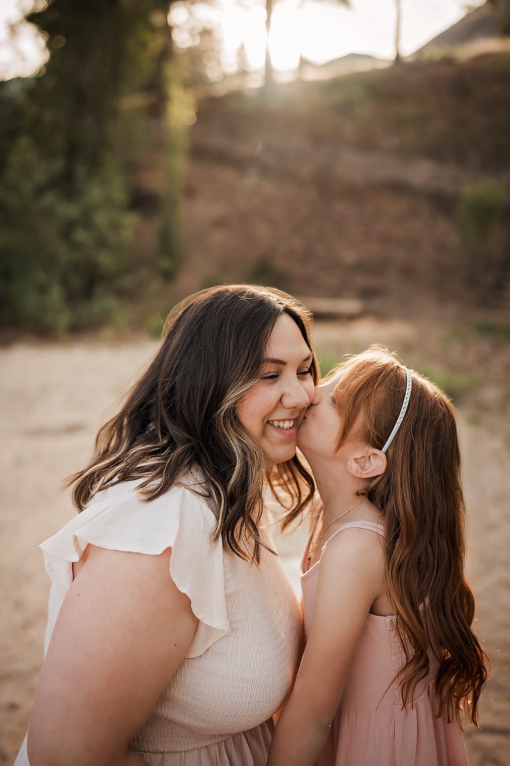 Mom and daughter share a cheek kiss during a Boise family session at golden hour