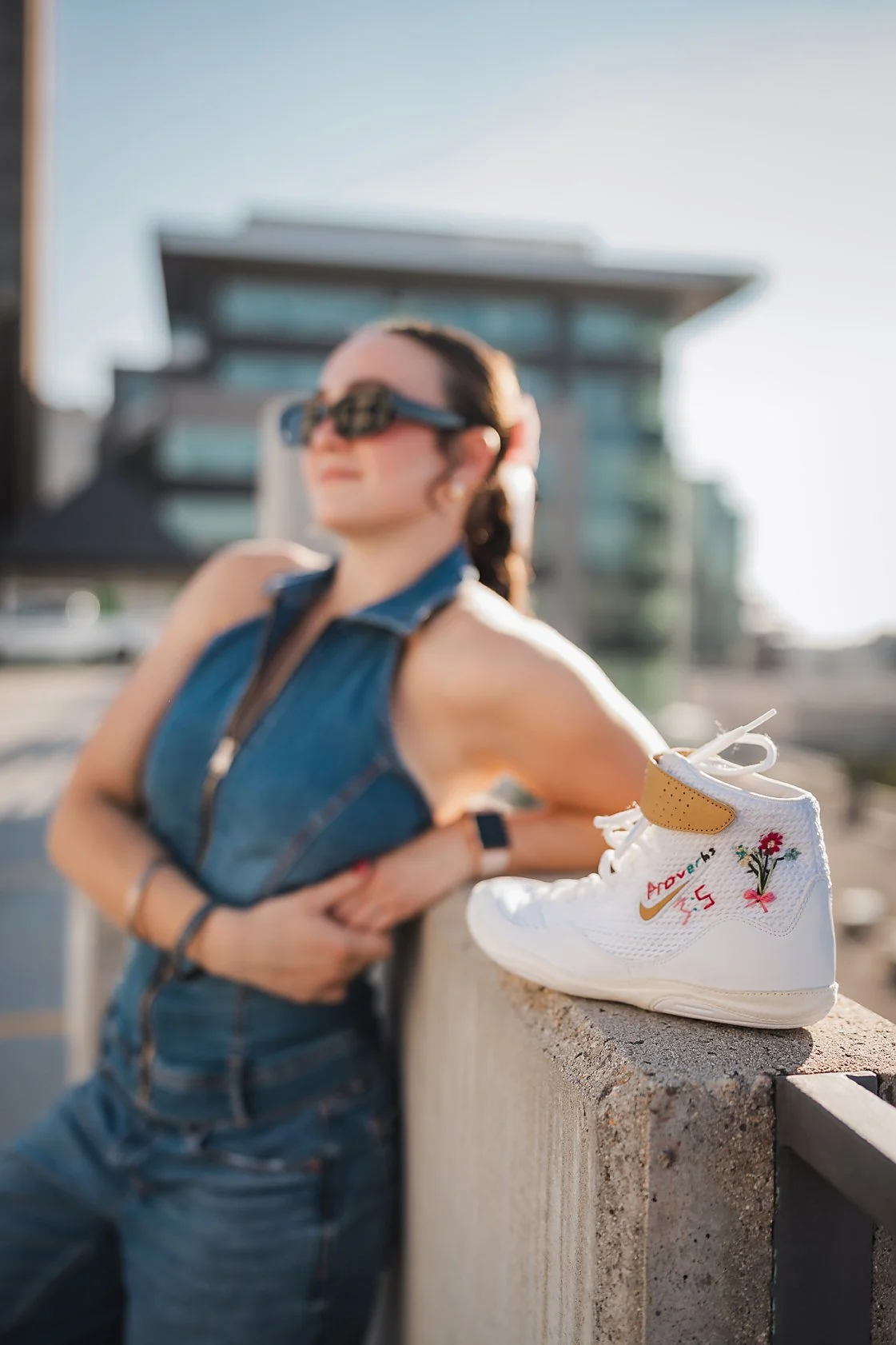 Eagle High School senior wrestler leaning on a downtown Boise ledge with custom flower-embroidered wrestling shoes