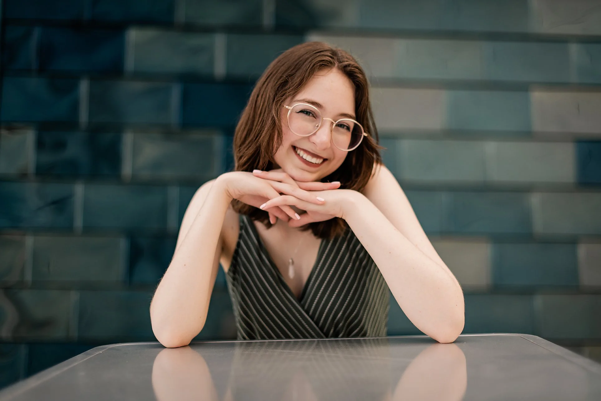 High school senior girl with glasses smiling at a table on Boise State University campus, Boise Idaho senior photographer
