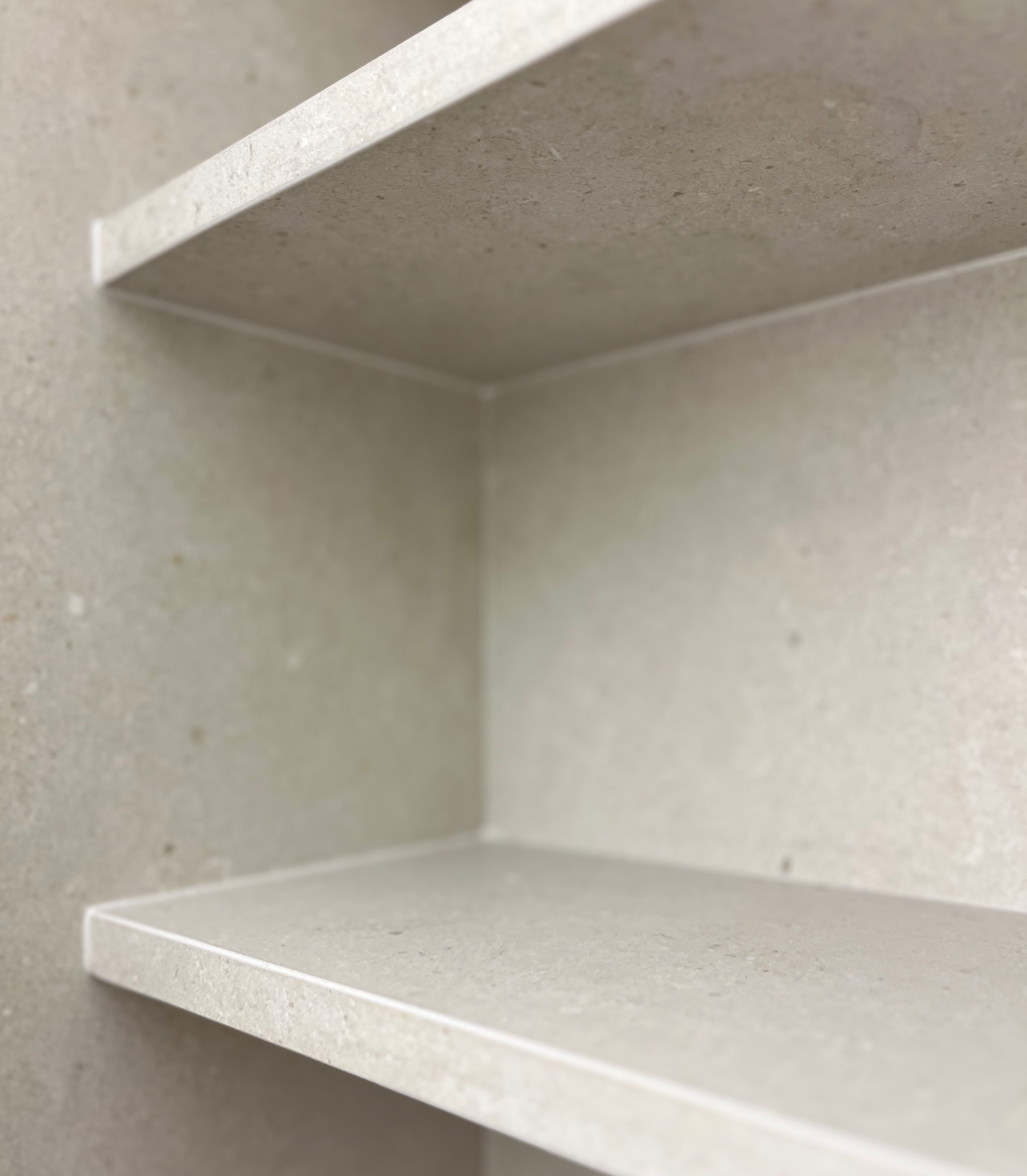 Detailný záber na prázdne biele police vo svetlej miestnosti.