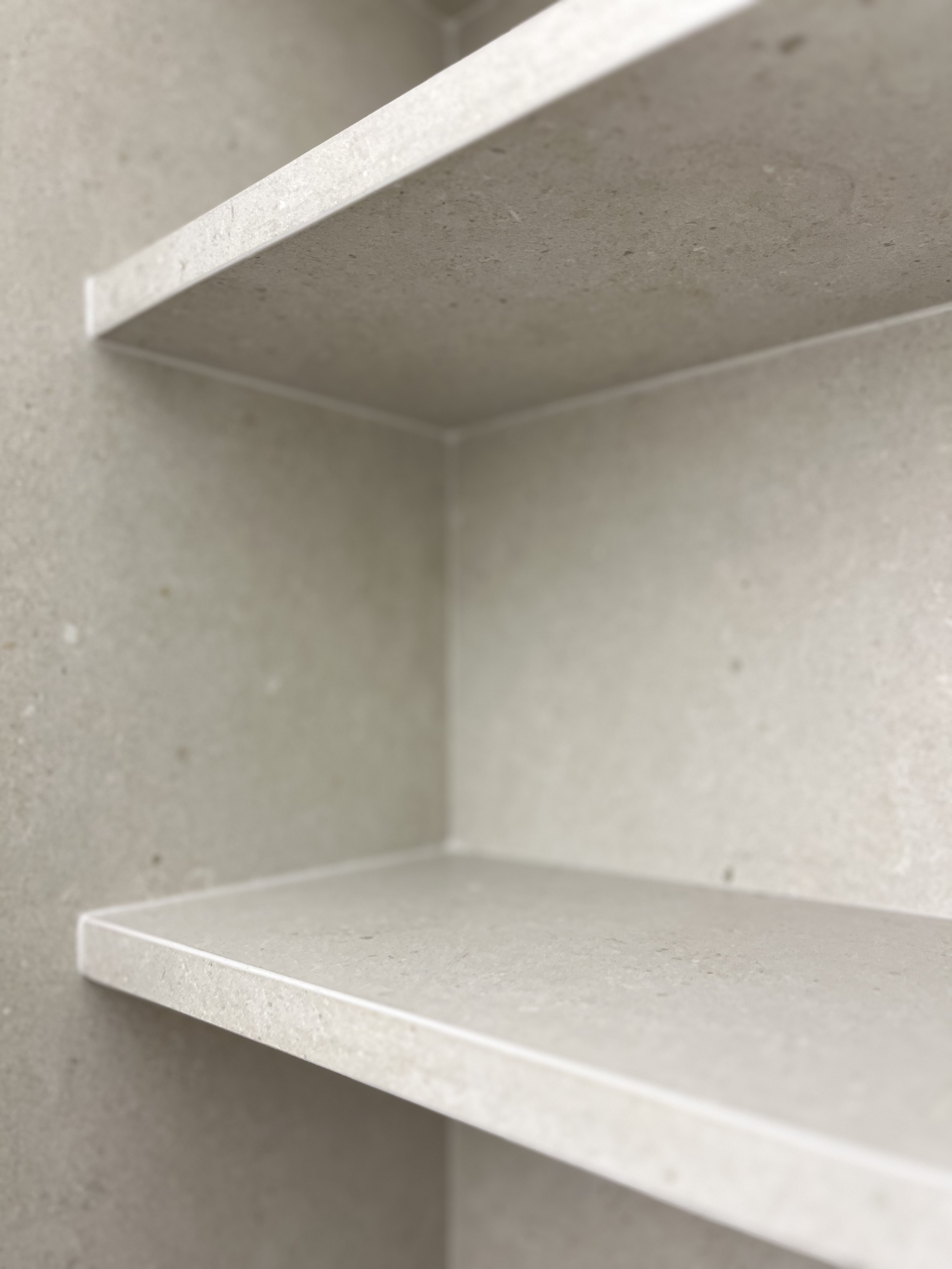 Close-up of empty corner white shelves in a light-colored room.