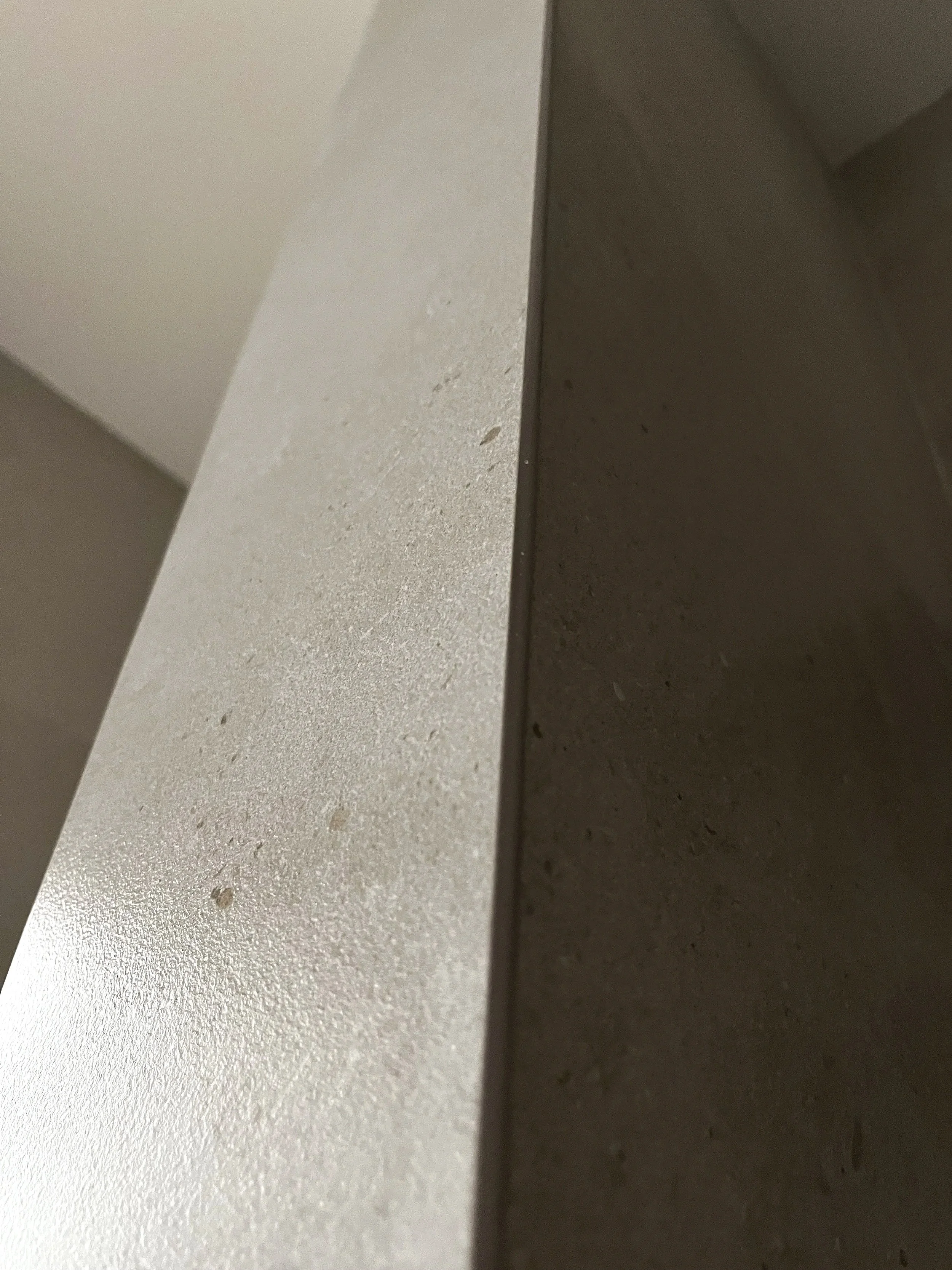 Close-up of a beige countertop or shelf surface with a smooth, matte finish and a slightly textured appearance.