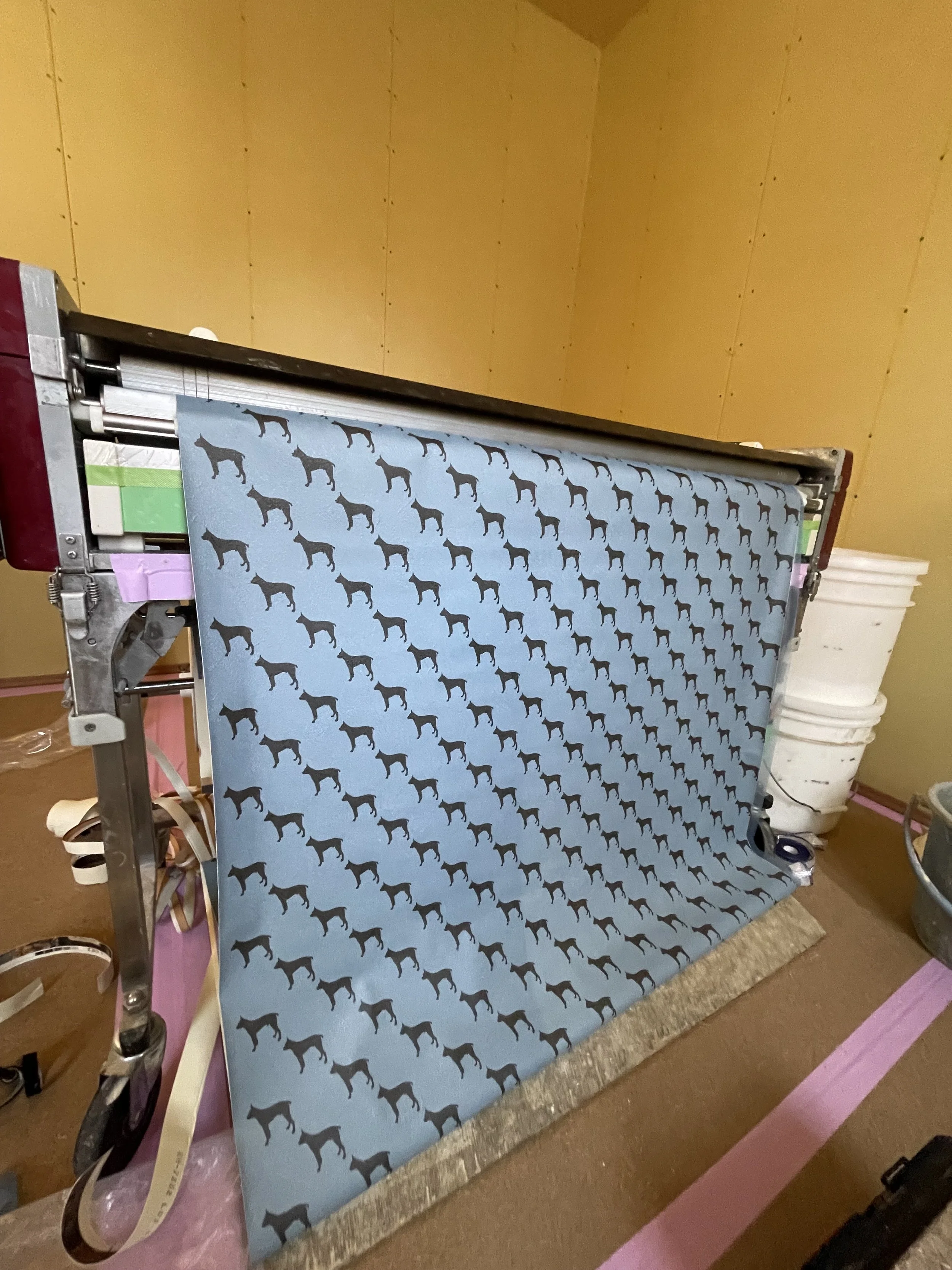 犬のパターンが施された壁紙が印刷機から出ている様子。