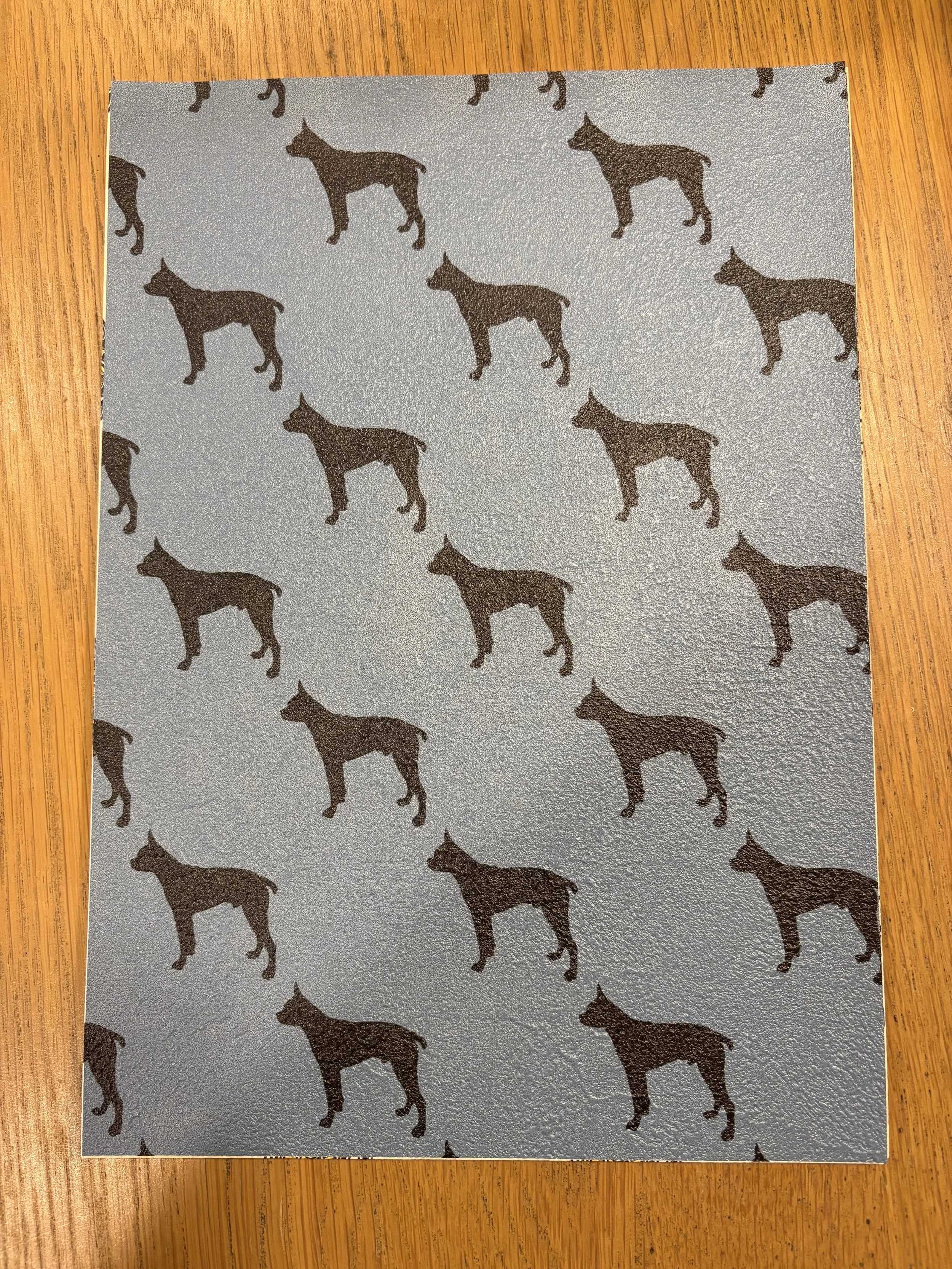 青い背景に黒い犬のシルエットが繰り返し配置された模様の紙。