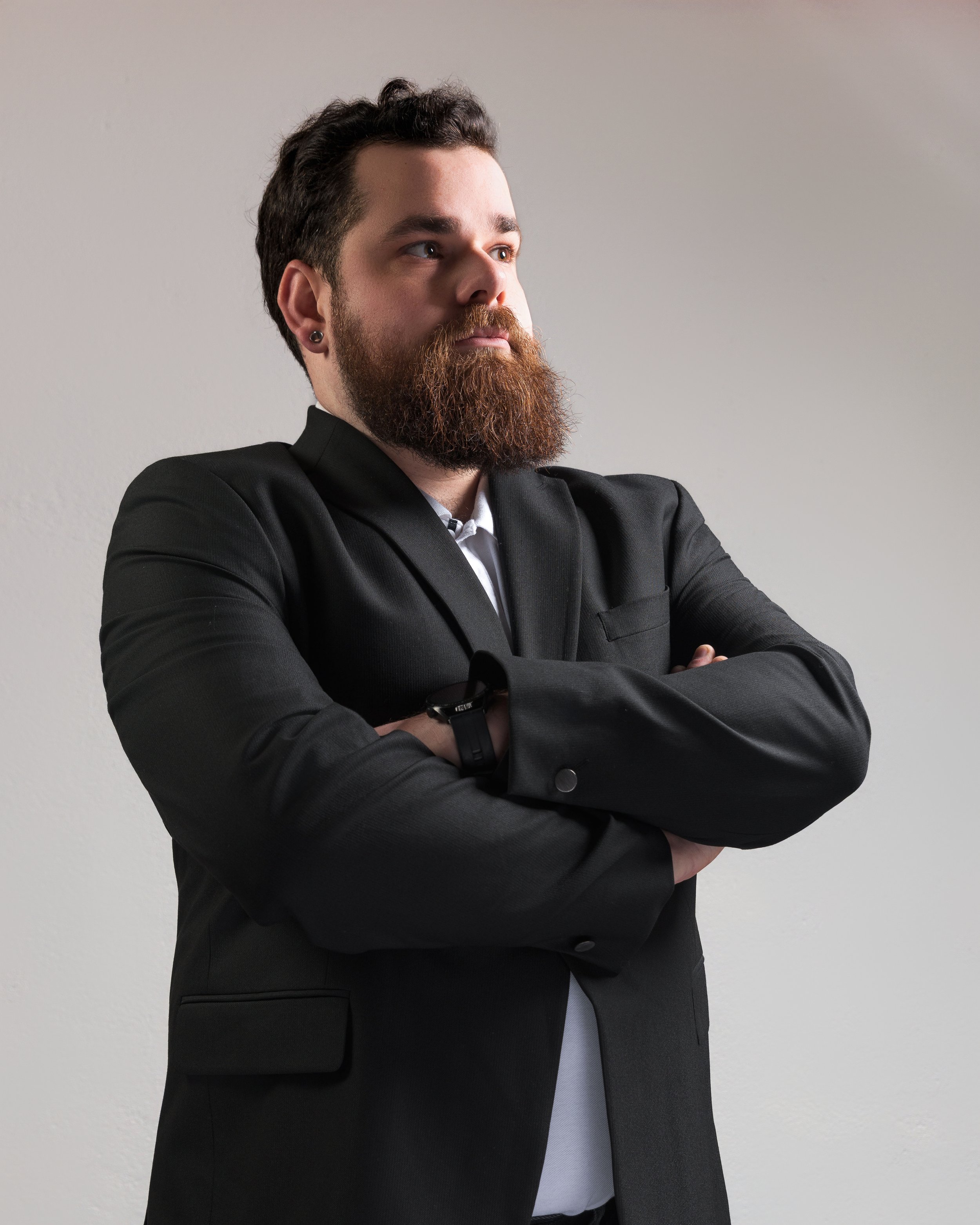 Un homme barbu, en tenue professionnel les bras croiser