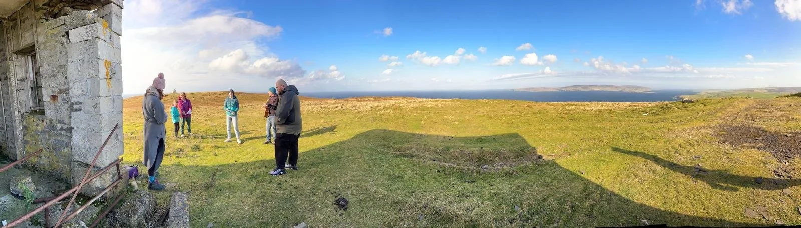 A group standing in a circle amidst a panoramic view of land
